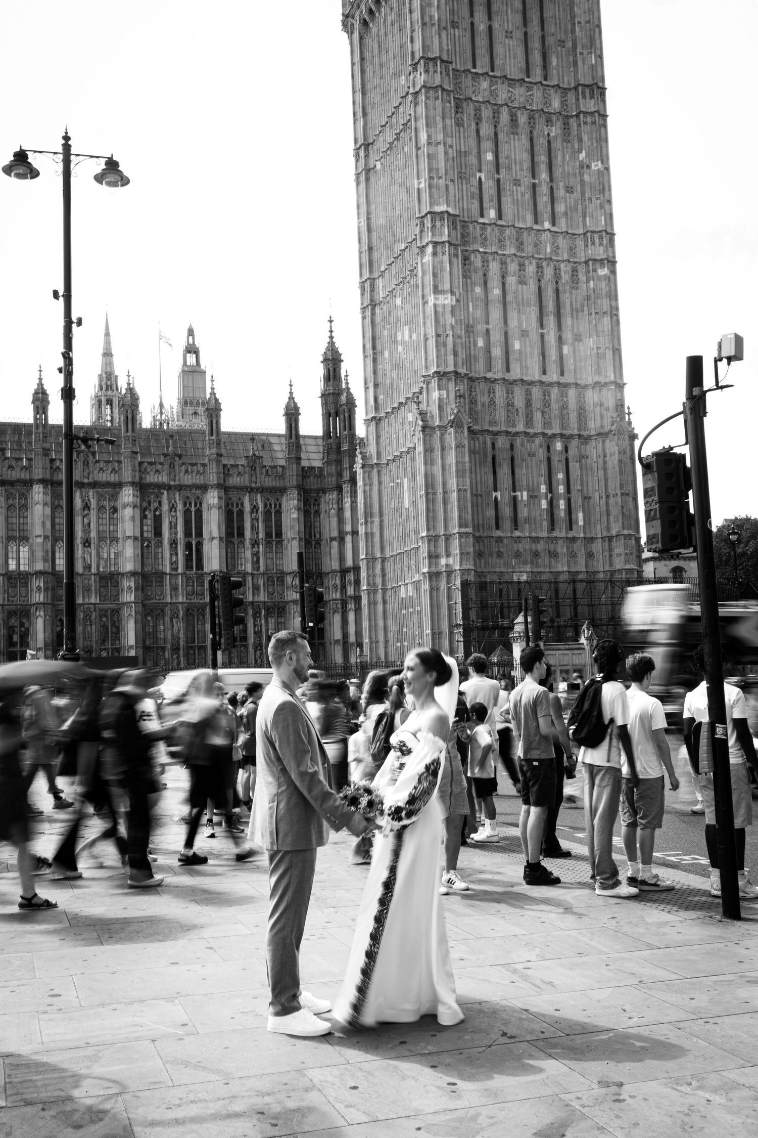Black and white photo of a wedding couple holding hands near Big Ben and the Houses of Parliament in London.