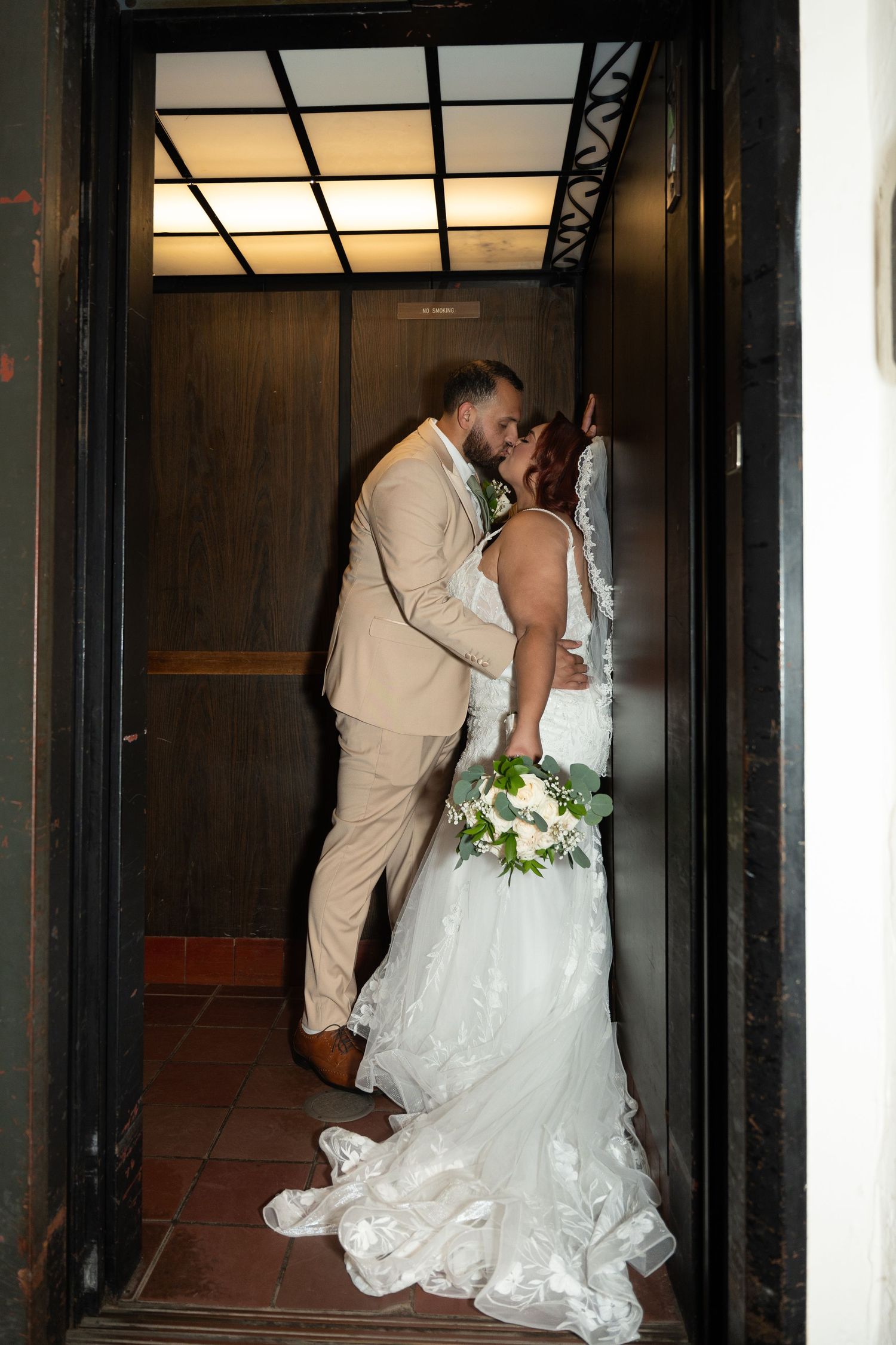 Intimate wedding portrait captured in warm-lit wooden hallway.