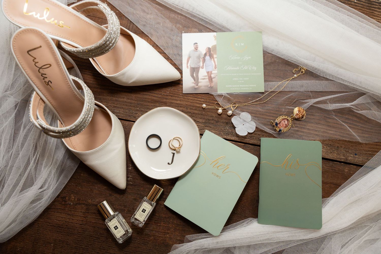 Wedding accessories including white heels and mint green cards arranged on rustic wooden surface.
