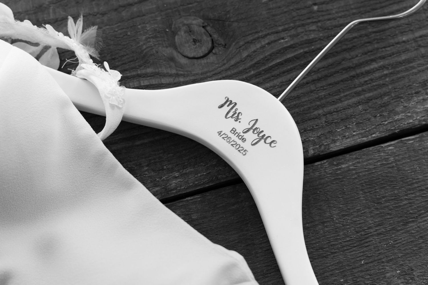 White wooden coat hangers with names inscribed hanging against a dark wooden background.
