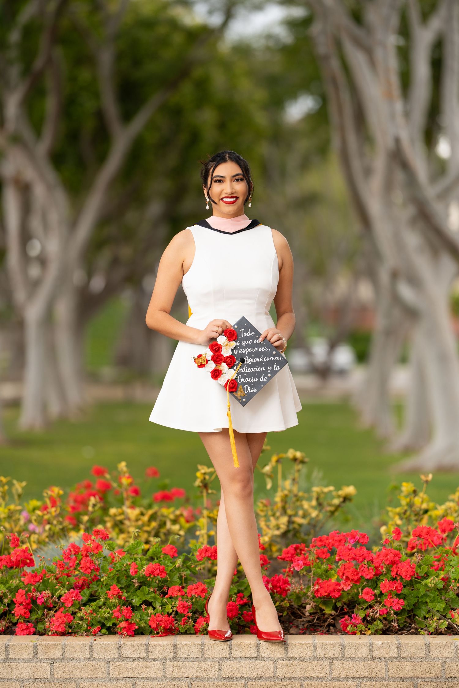 A sequence of four photos showing someone in a white dress sitting on a brick wall with red and yellow flowers below.