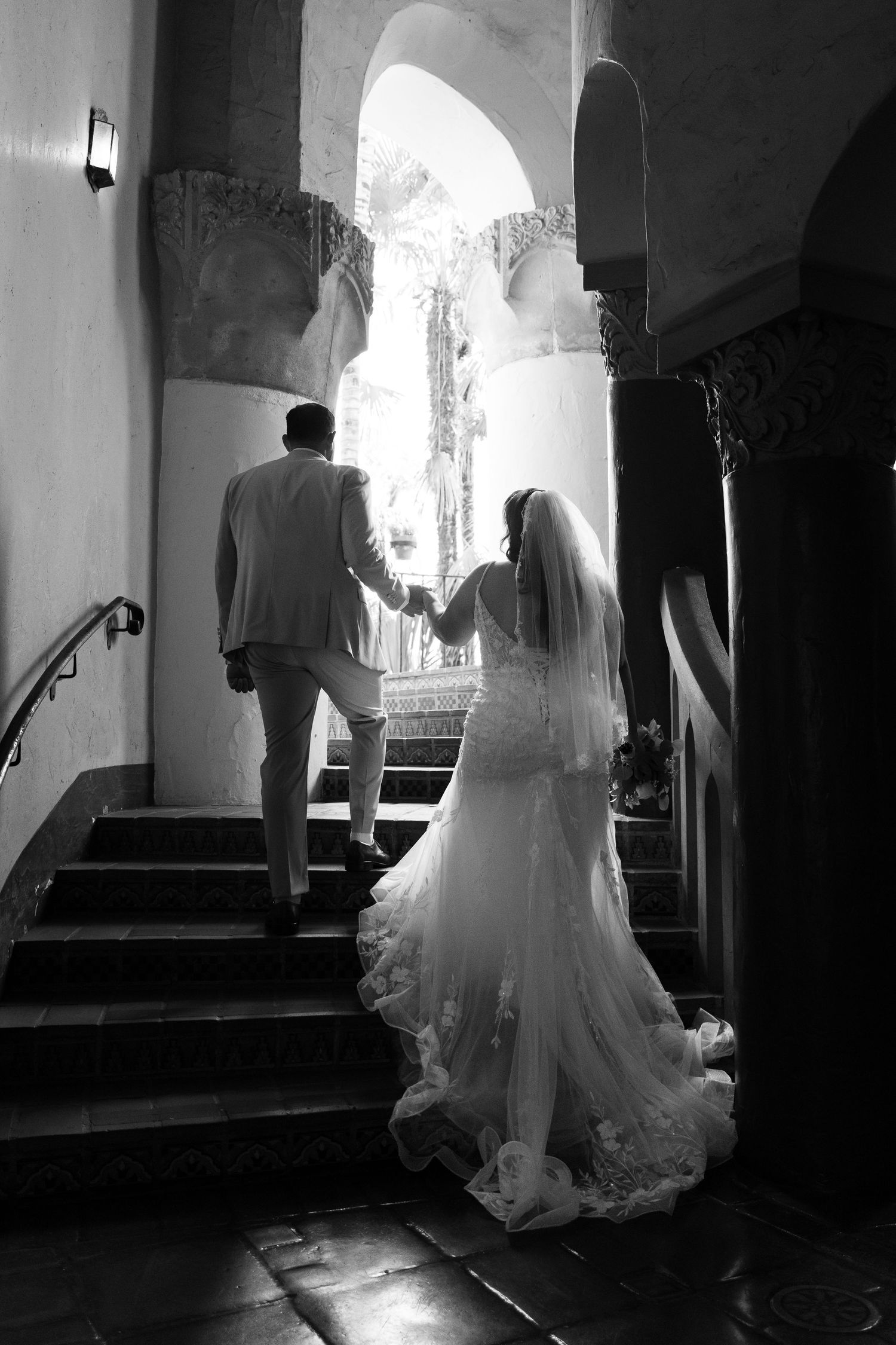 Silhouetted wedding dress and figures in dramatic archway lighting.