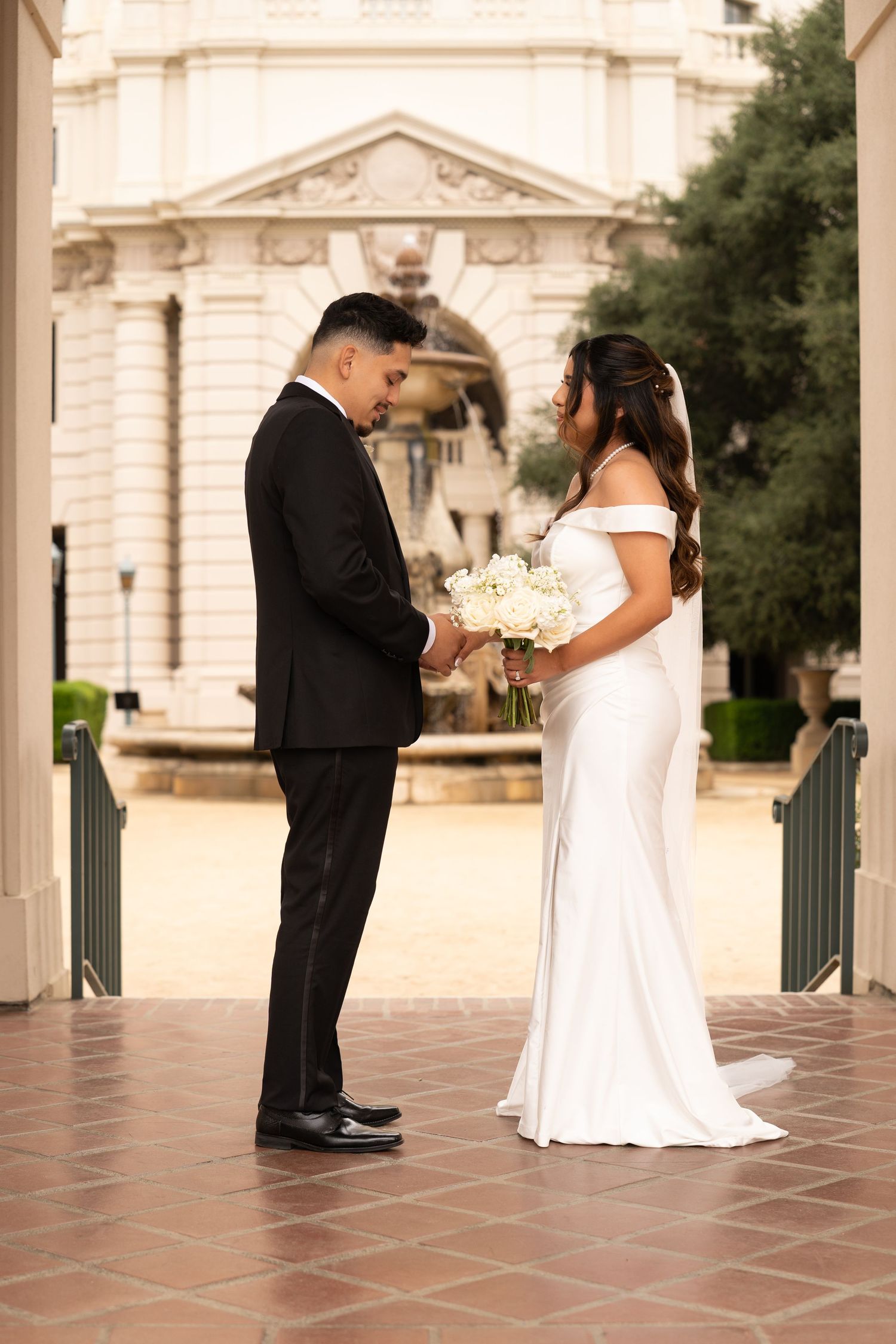 A wedding ceremony moment on a tiled terrace with classical architecture in the background.