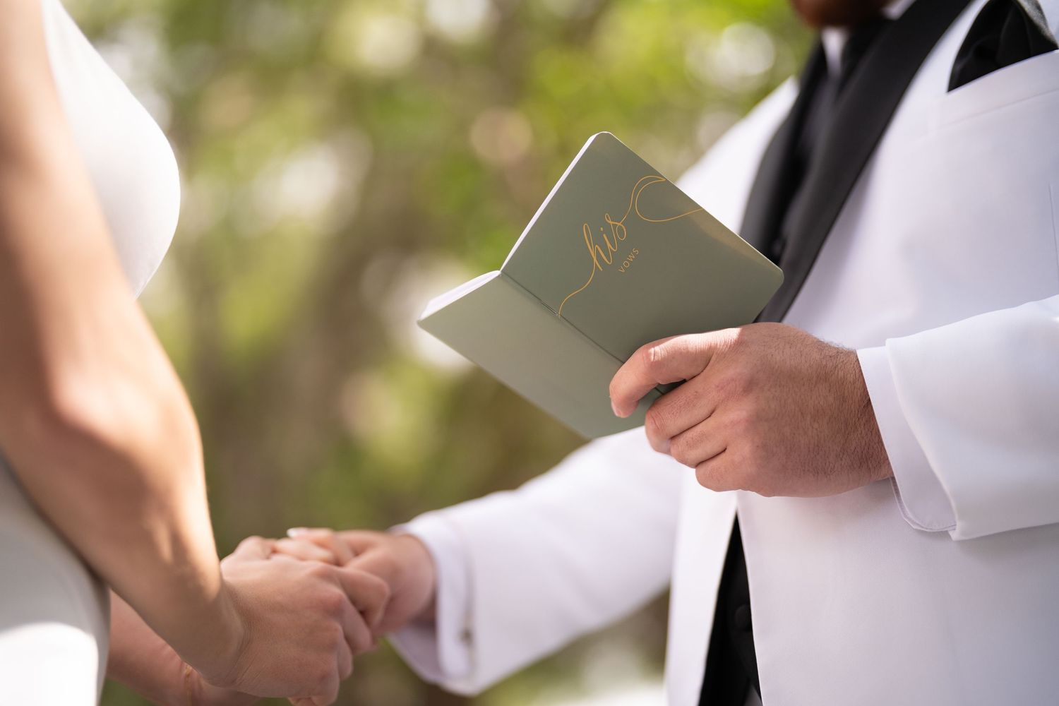 Close-up of hands holding a wedding ceremony book during an outdoor service.