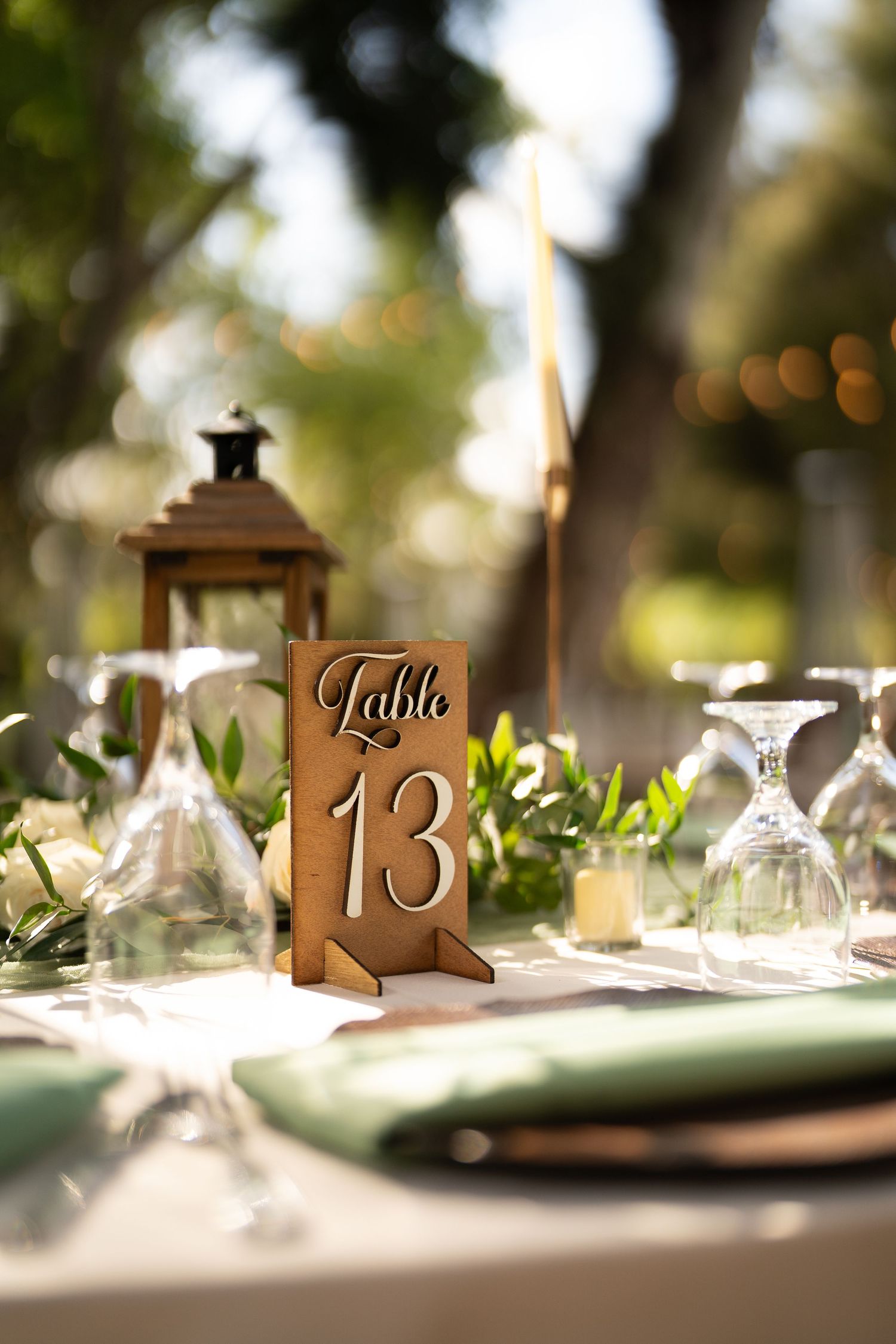 Rustic table setting with wooden table number and lantern centerpiece.