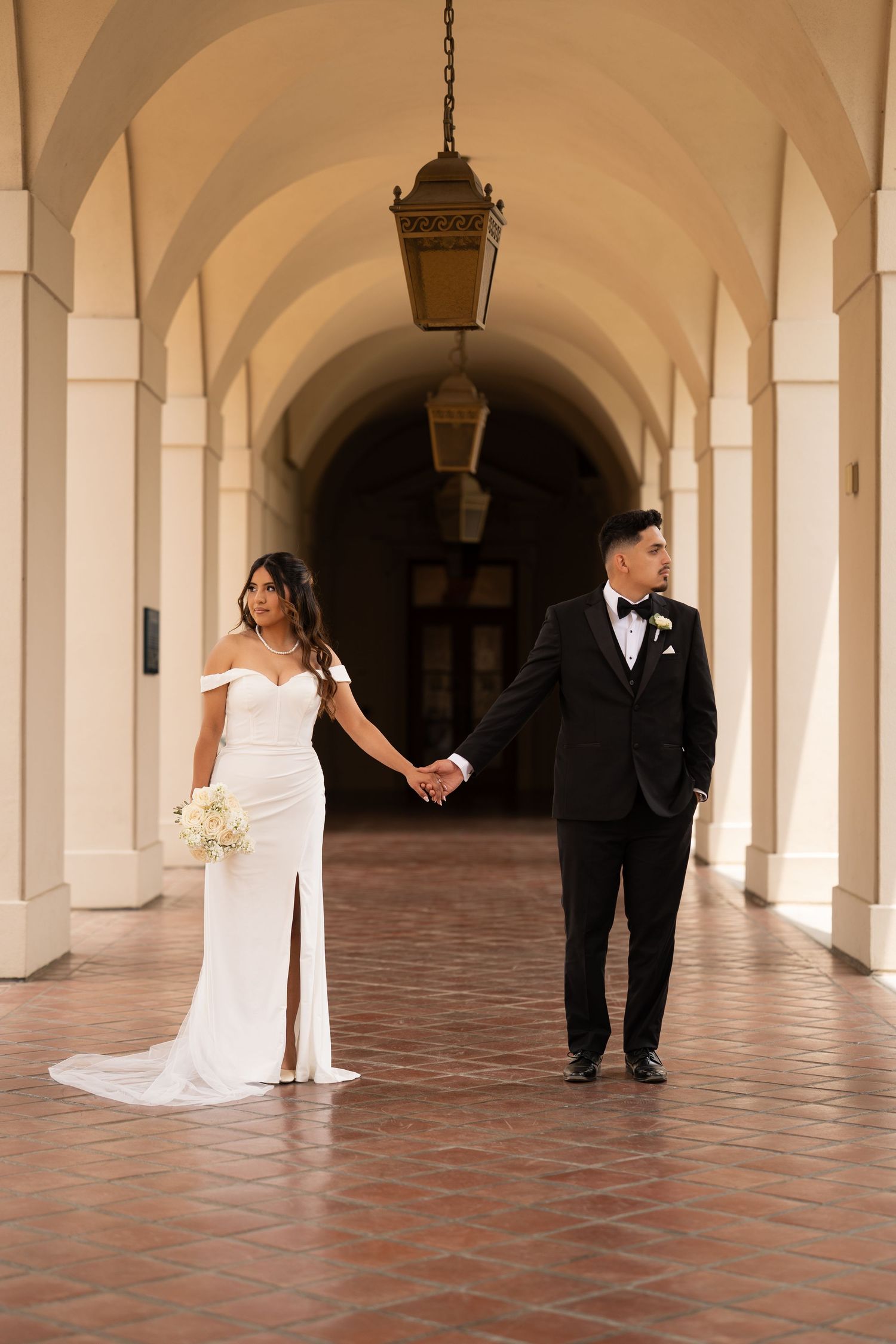 Wedding couple captured in segments through arched hallway with hanging lanterns.