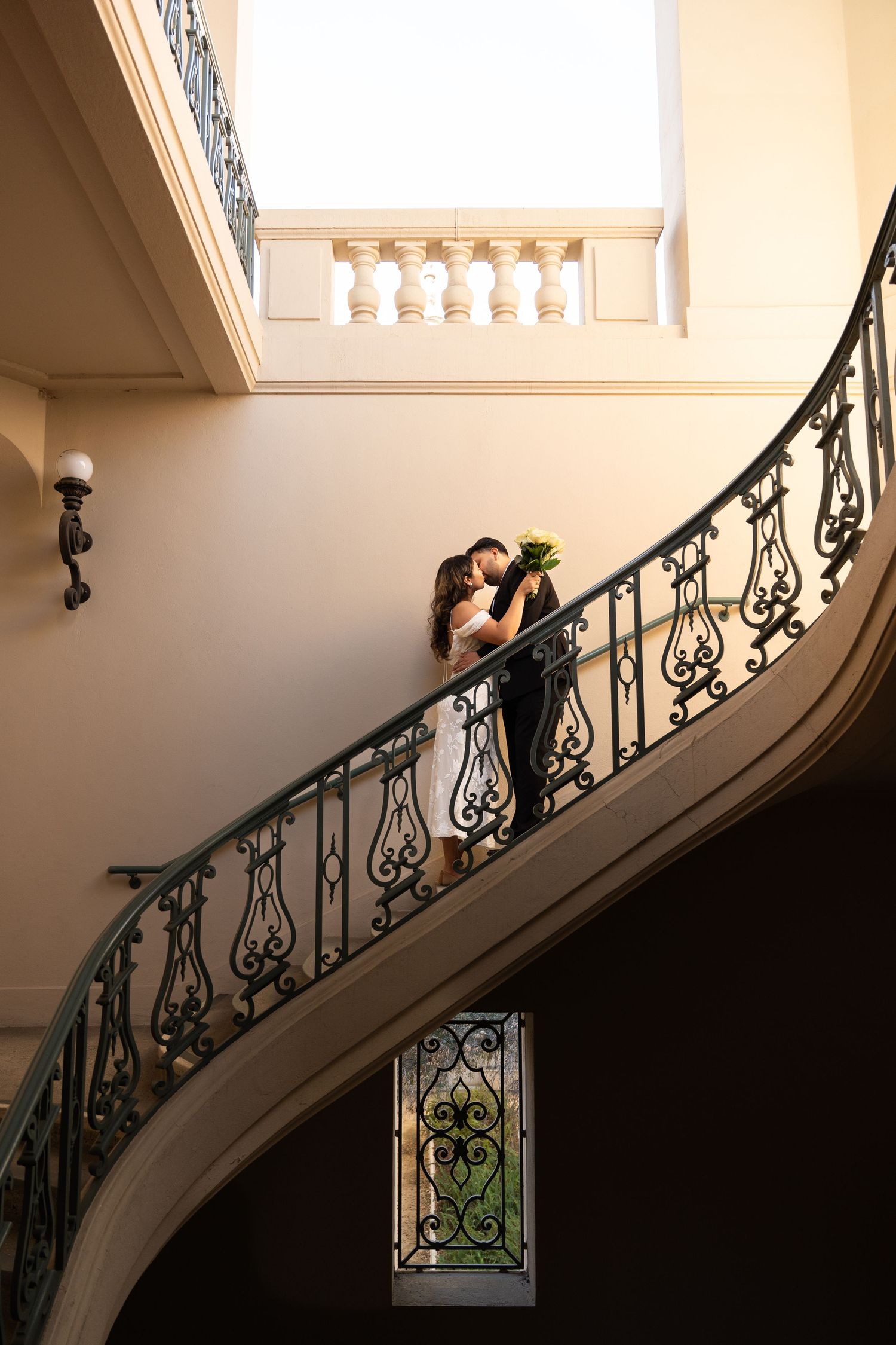 A series of silhouettes showing a couple along a curved staircase with ornate iron railings.