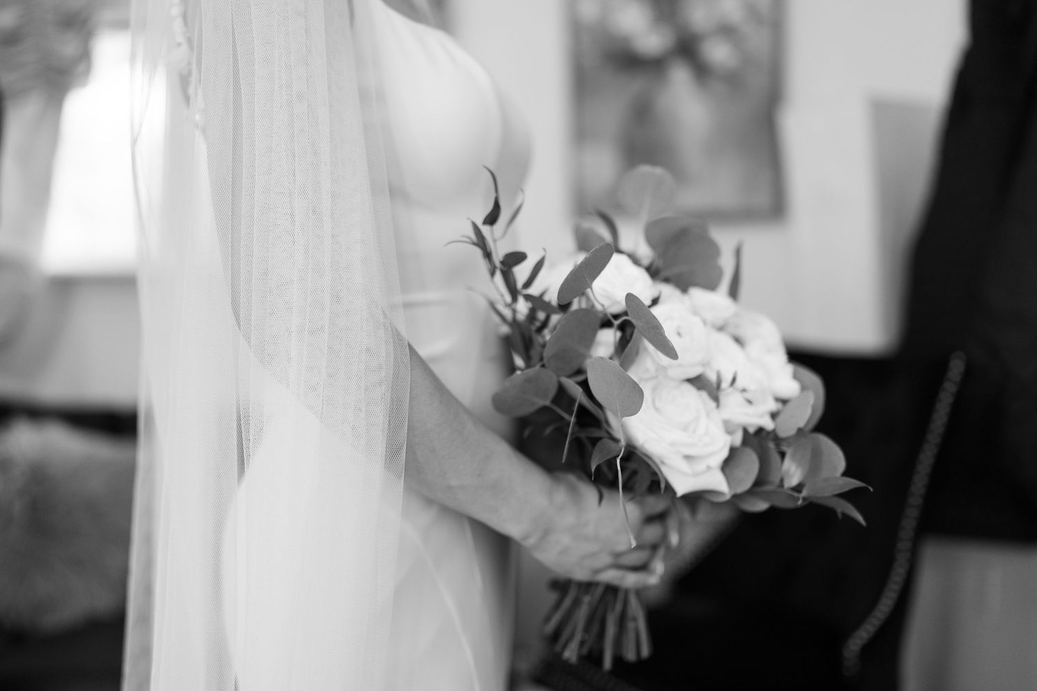Delicate bridal bouquet with white flowers against a veiled dress.