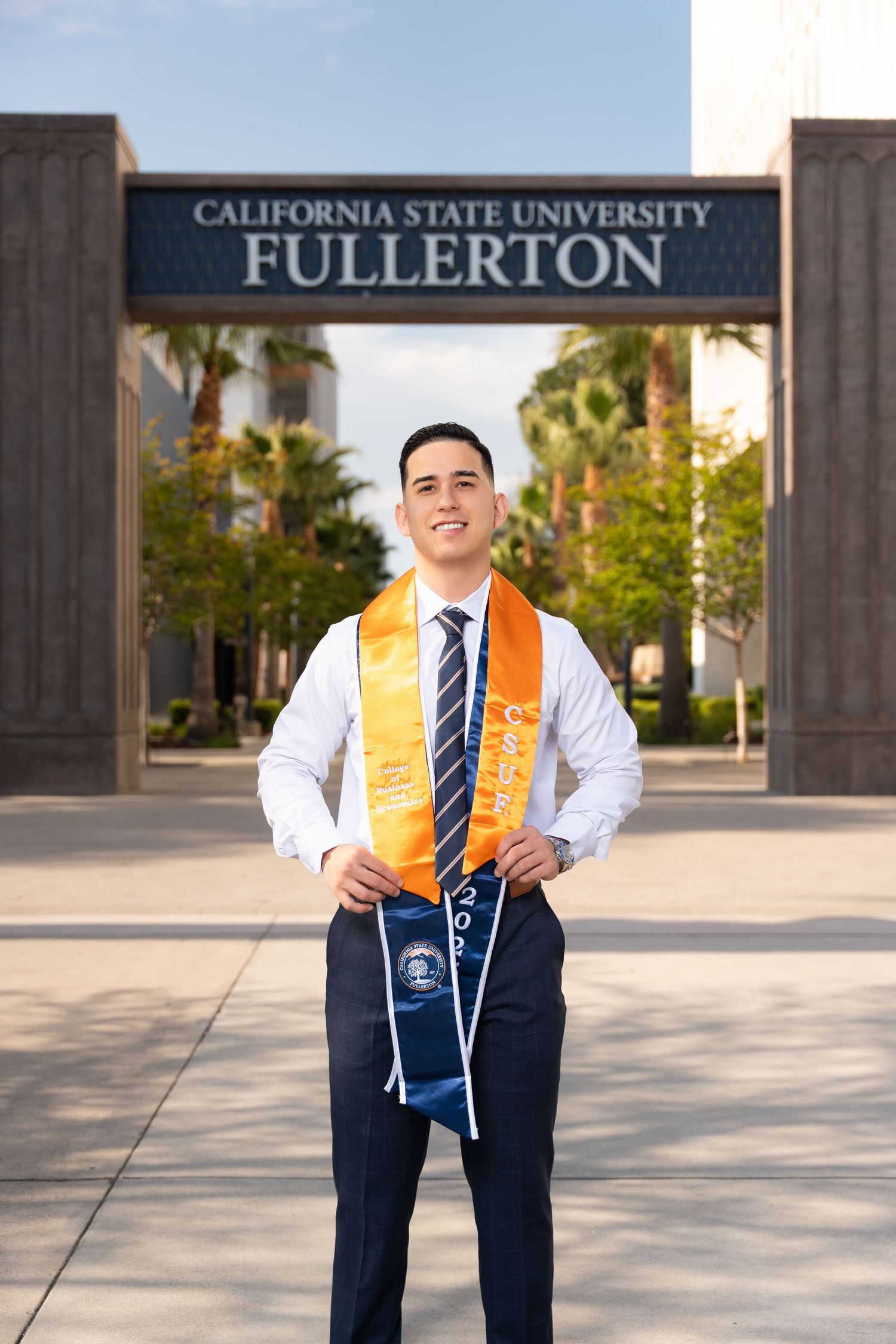 Graduate in cap and gown poses for graduation photos at California State University Fullerton campus.