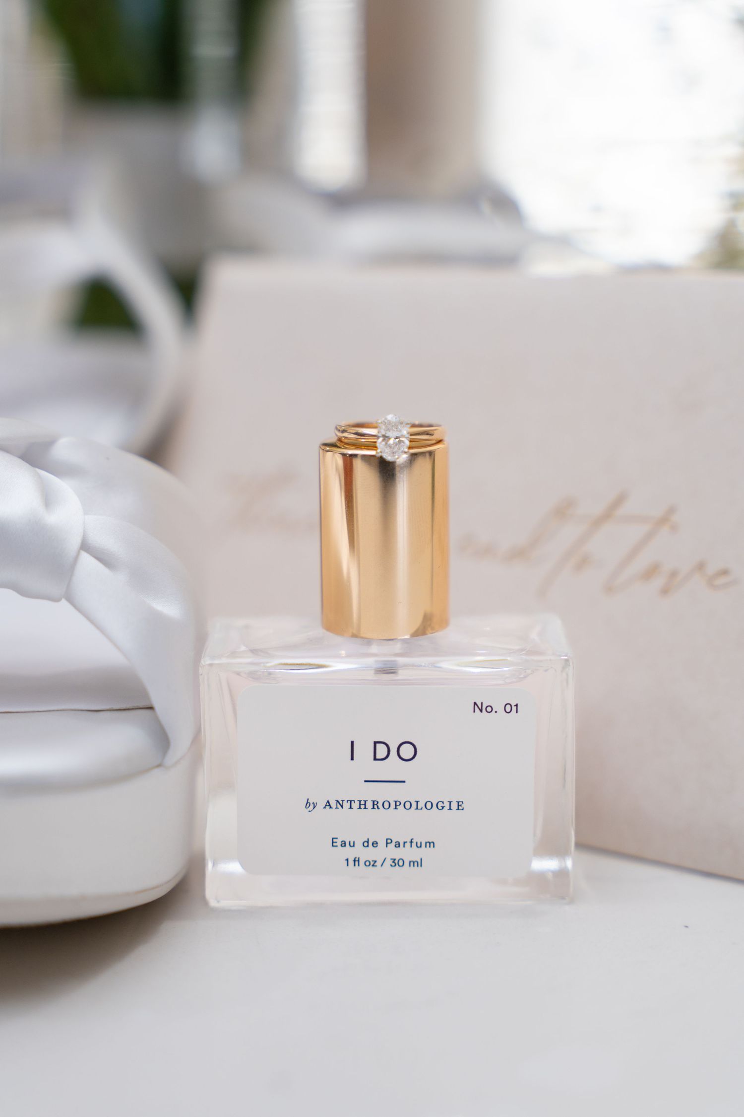 Elegant perfume bottle labeled 'I DO' with gold cap on white surface.
