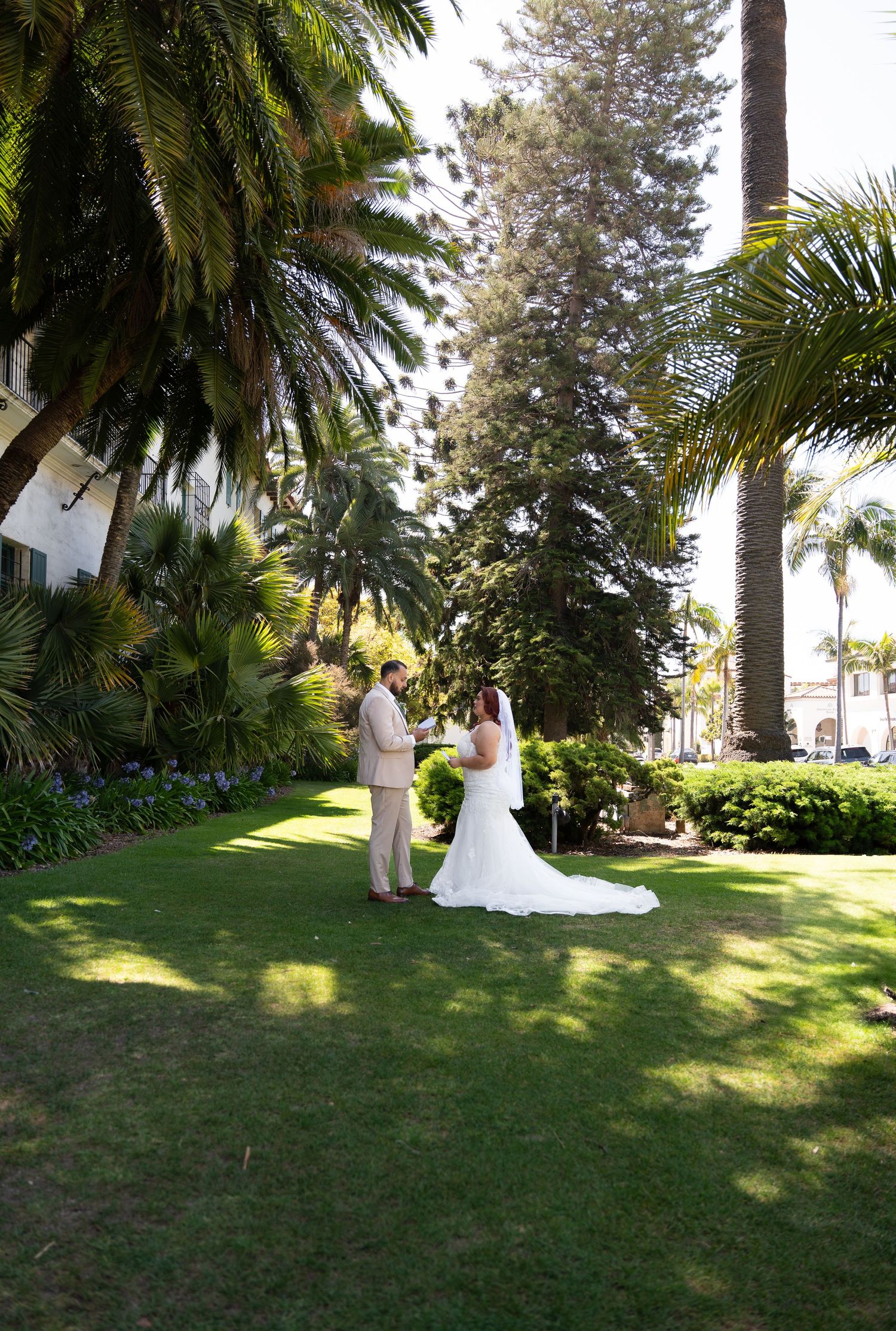 Wedding couple walking through a tropical garden with palm trees and lush greenery.