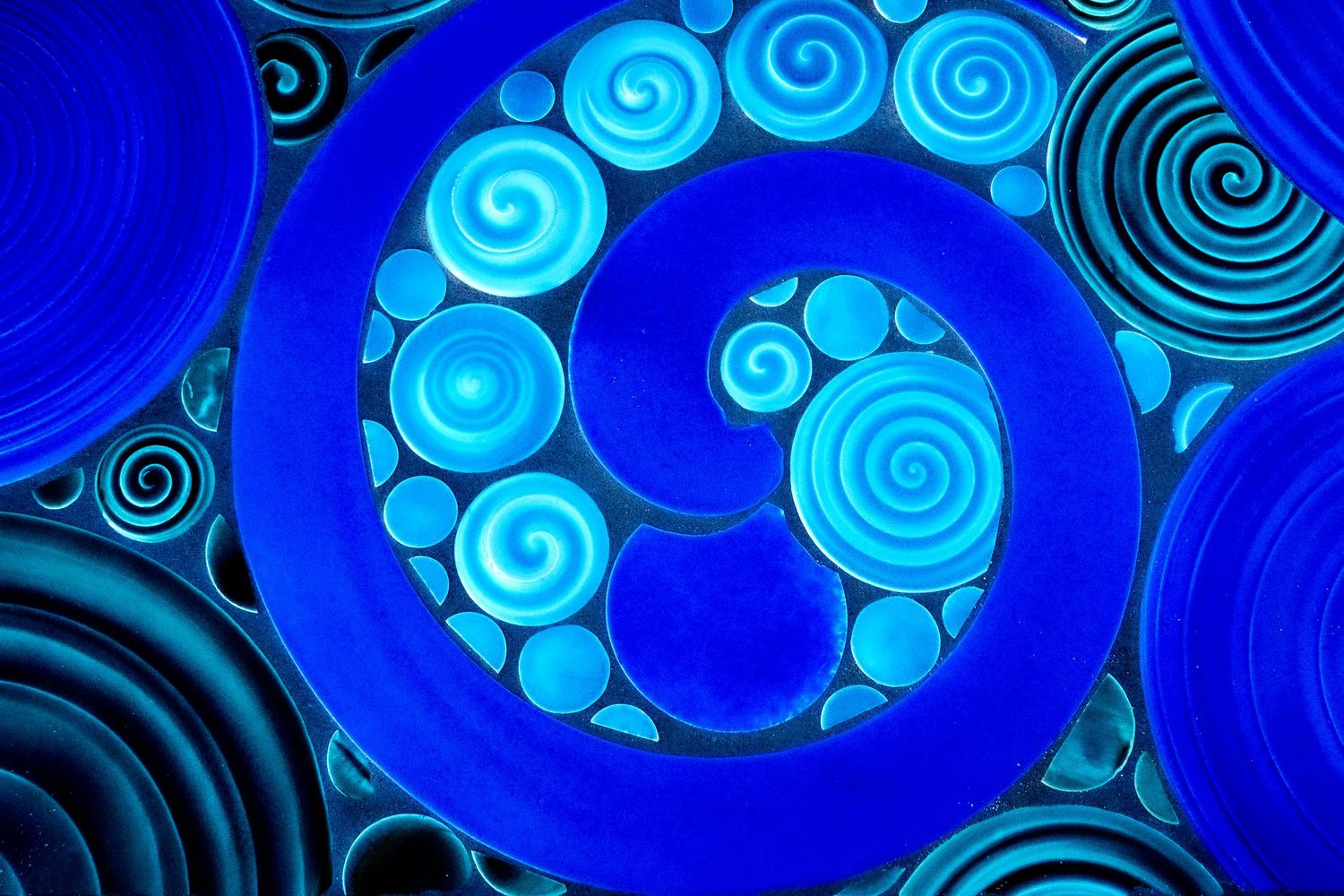 Spirals of varying sizes and shades of blue create an abstract pattern.