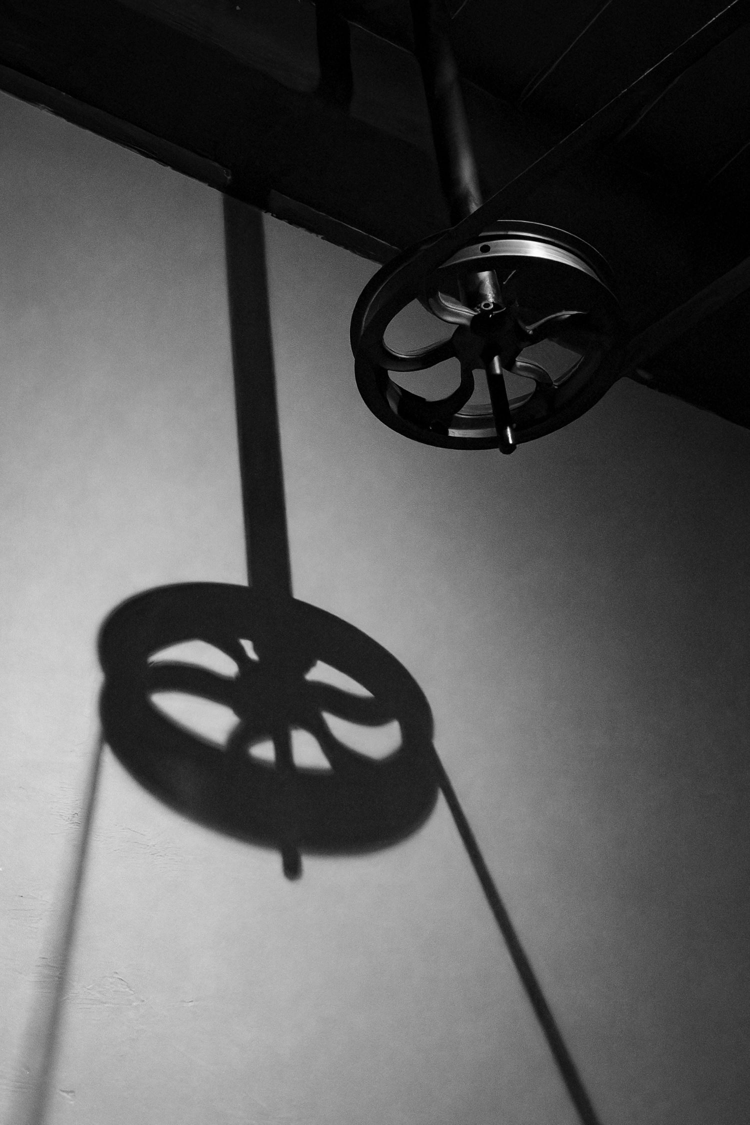 A pulley system casts a shadow on the wall in this black and white image.