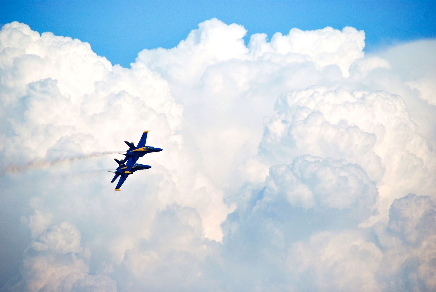 Two US Navy Blue Angels planes soar in the clouds at an air show.