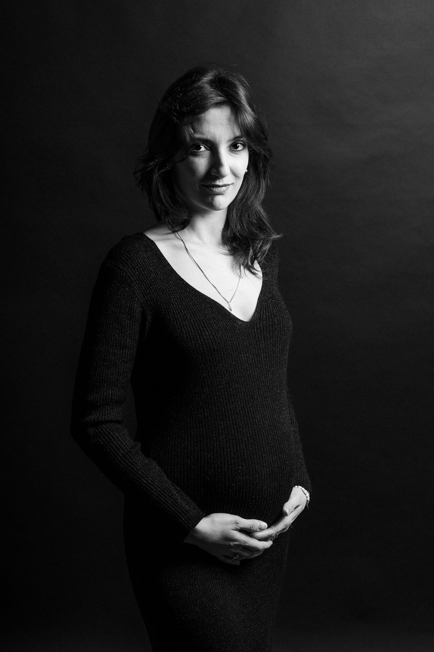 Black and white portrait series of person in dark sweater against dramatic background.