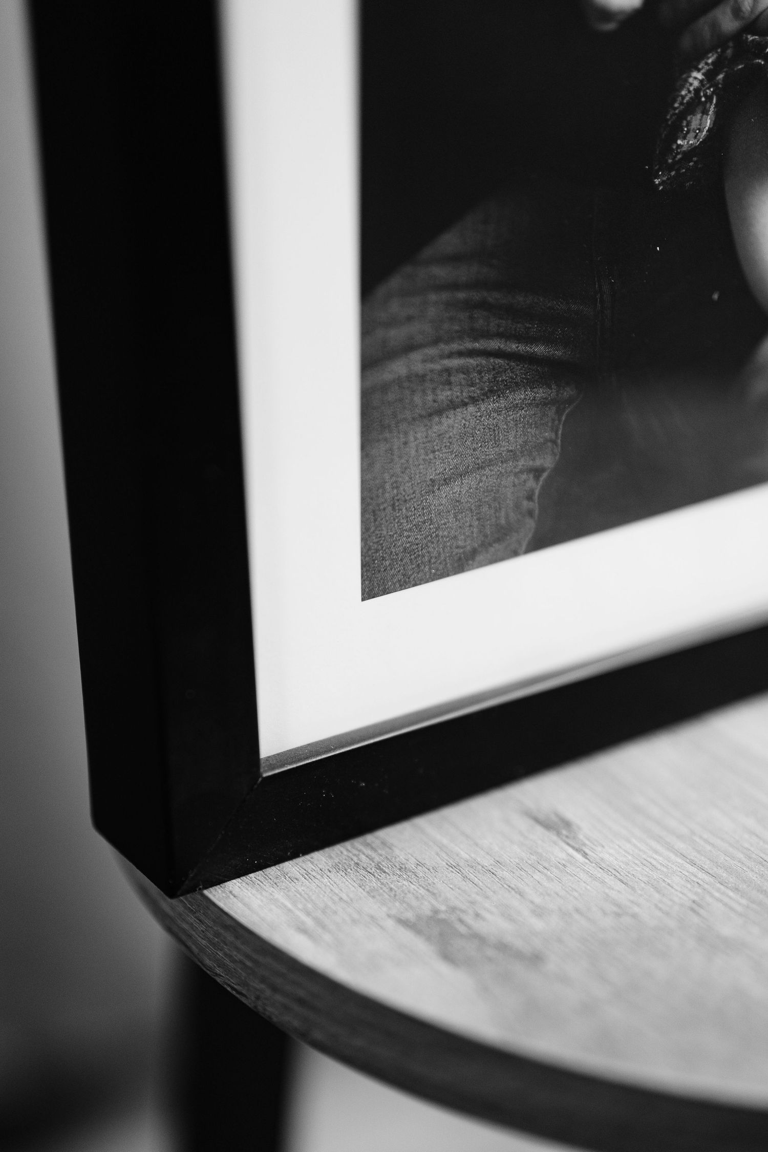 A close-up black and white photograph of framed photographs hanging on a wall with shallow depth of field.