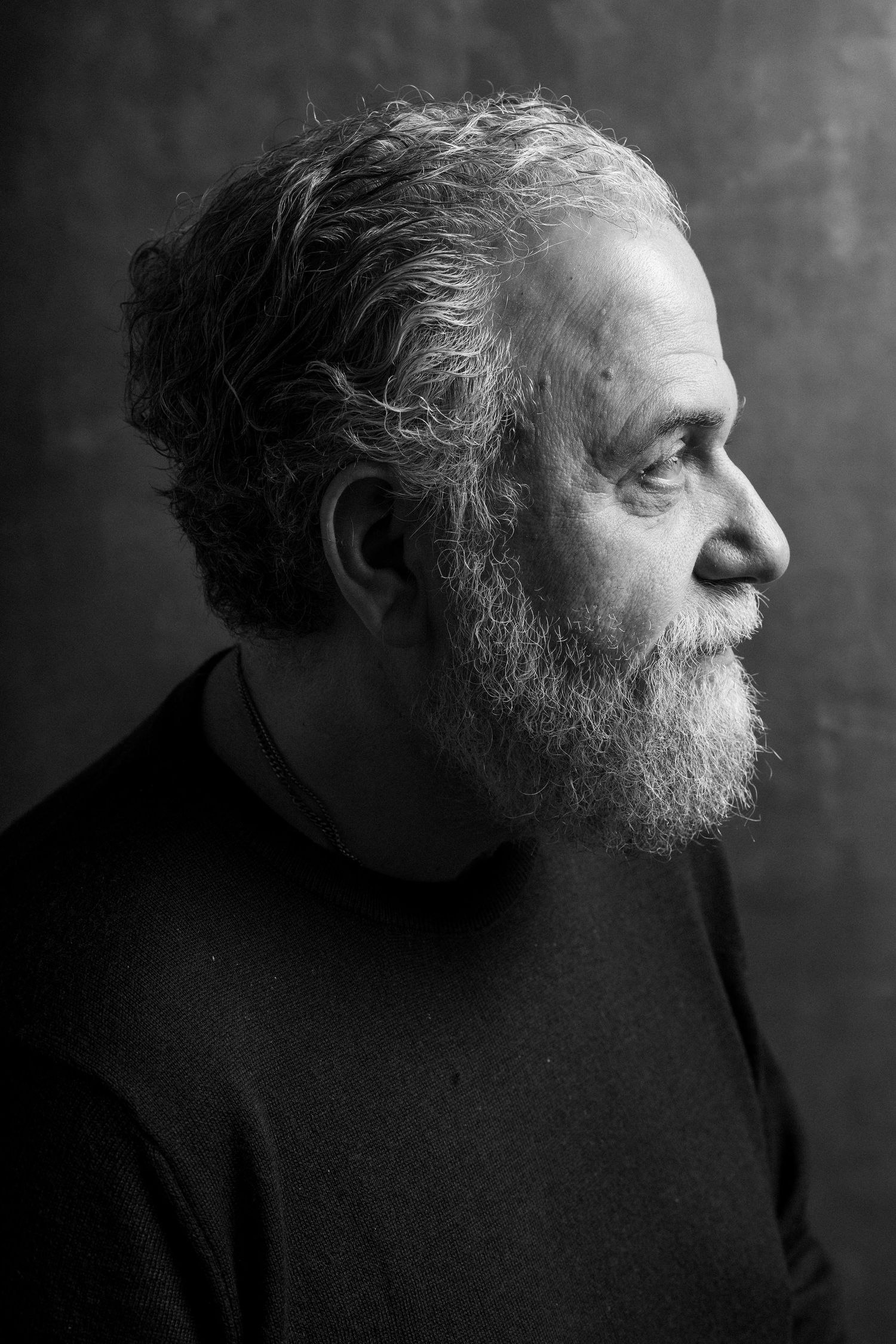 Black and white portrait sequence of a bearded person in dark clothing looking to the side.
