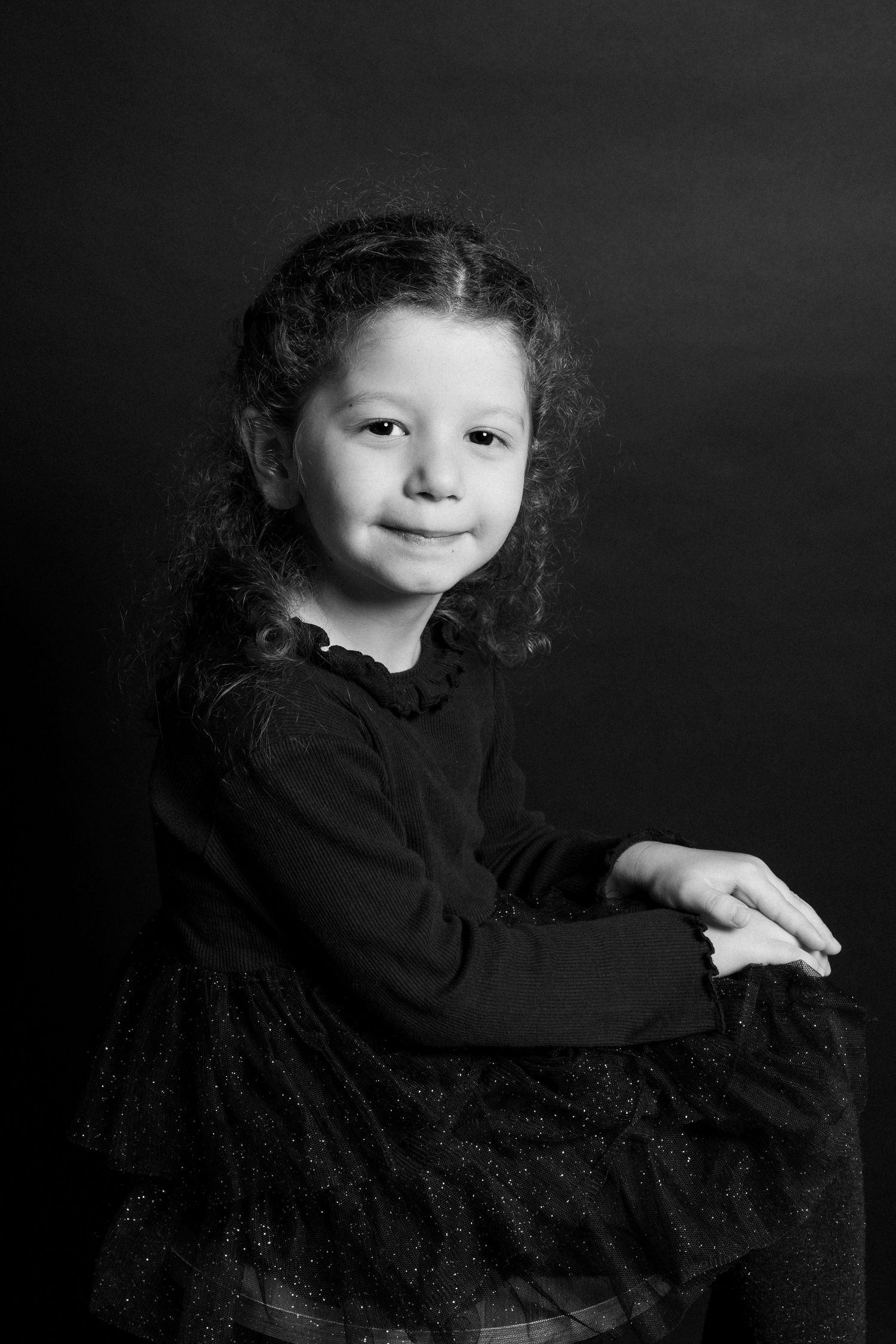 Black and white portrait series of a small child in dark clothing against a dark backdrop.