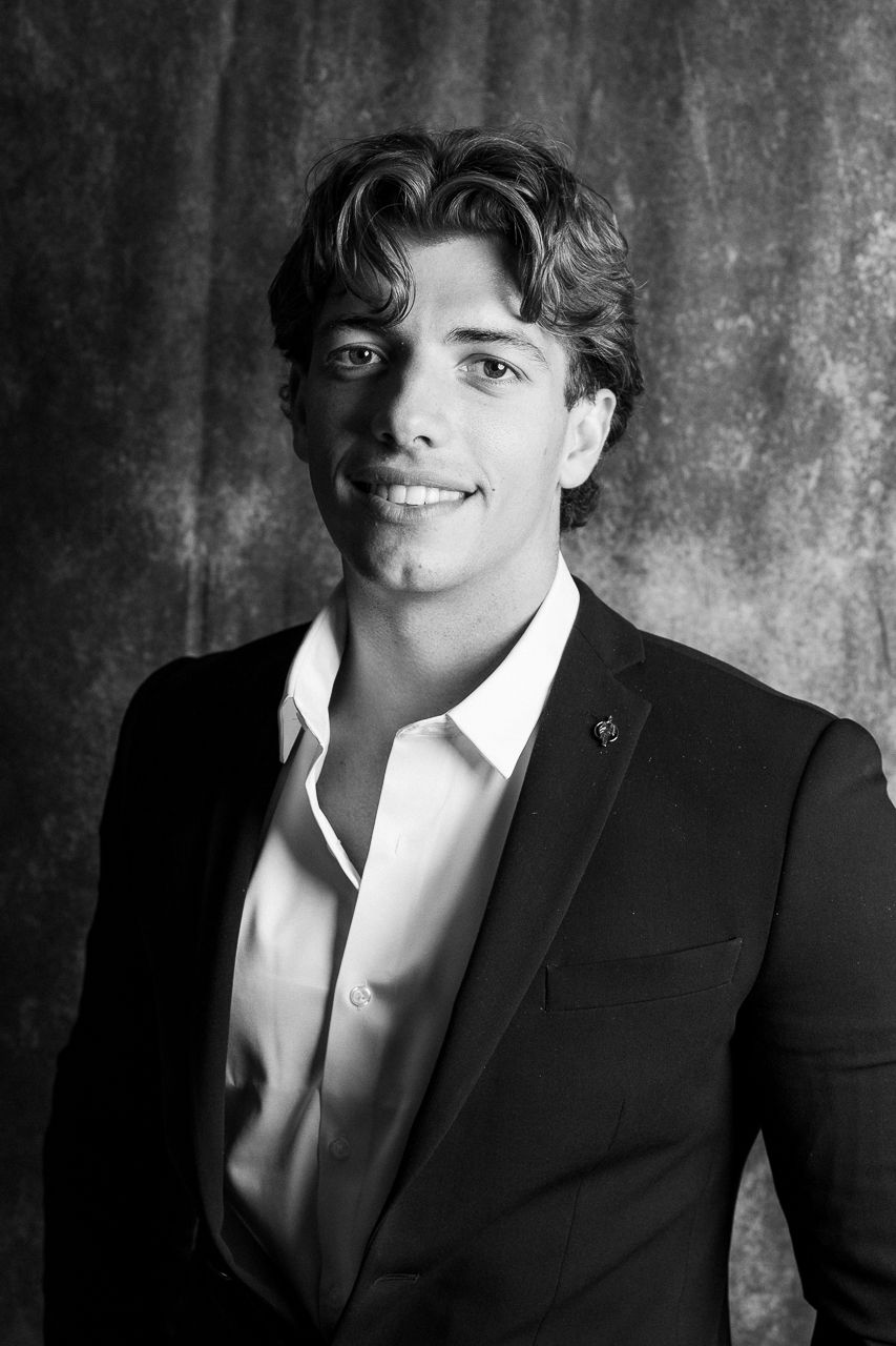 Dramatic black and white portrait series of person in suit against textured background.