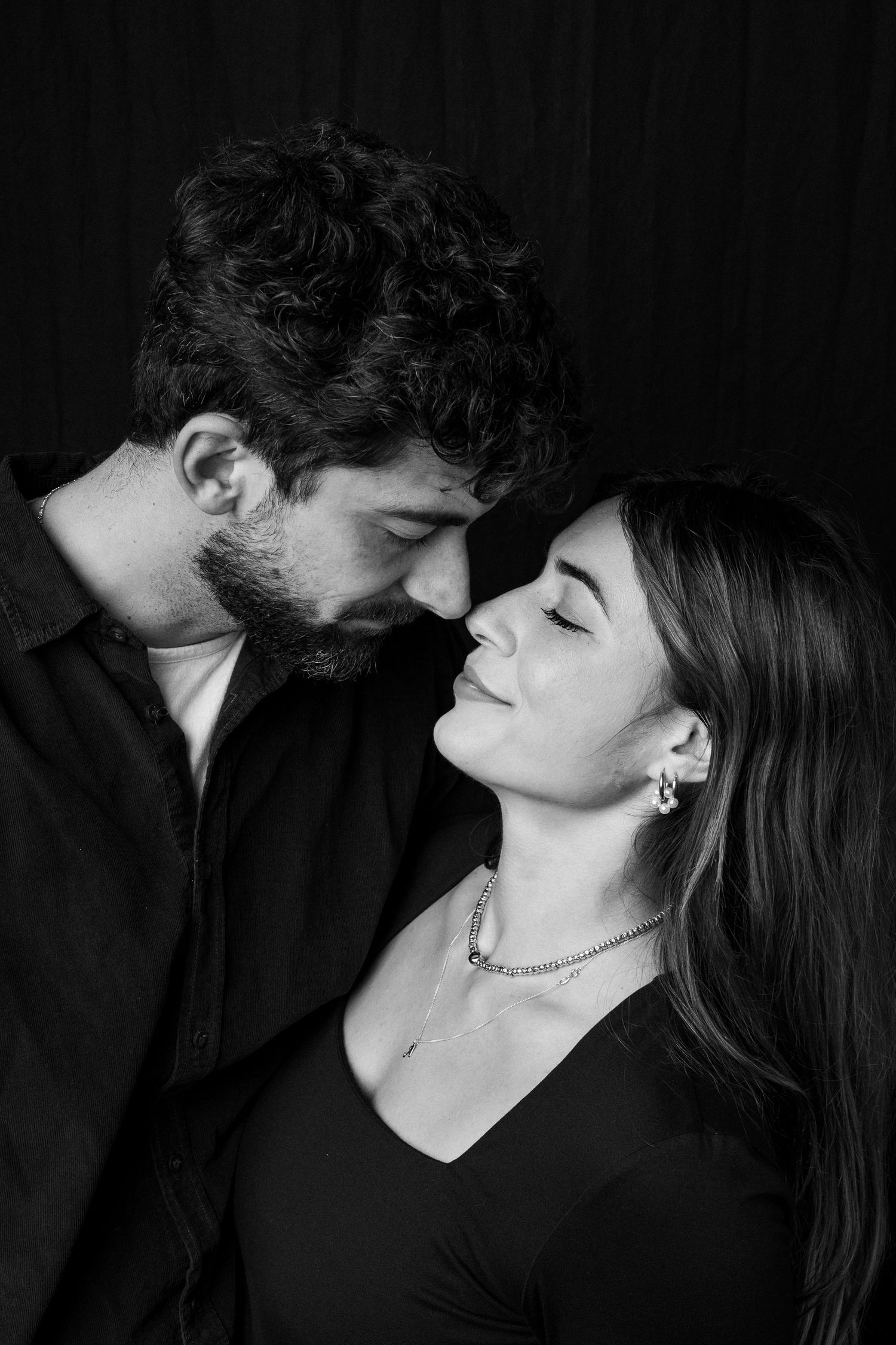 Romantic black and white portrait sequence of couple in intimate poses against dark backdrop.