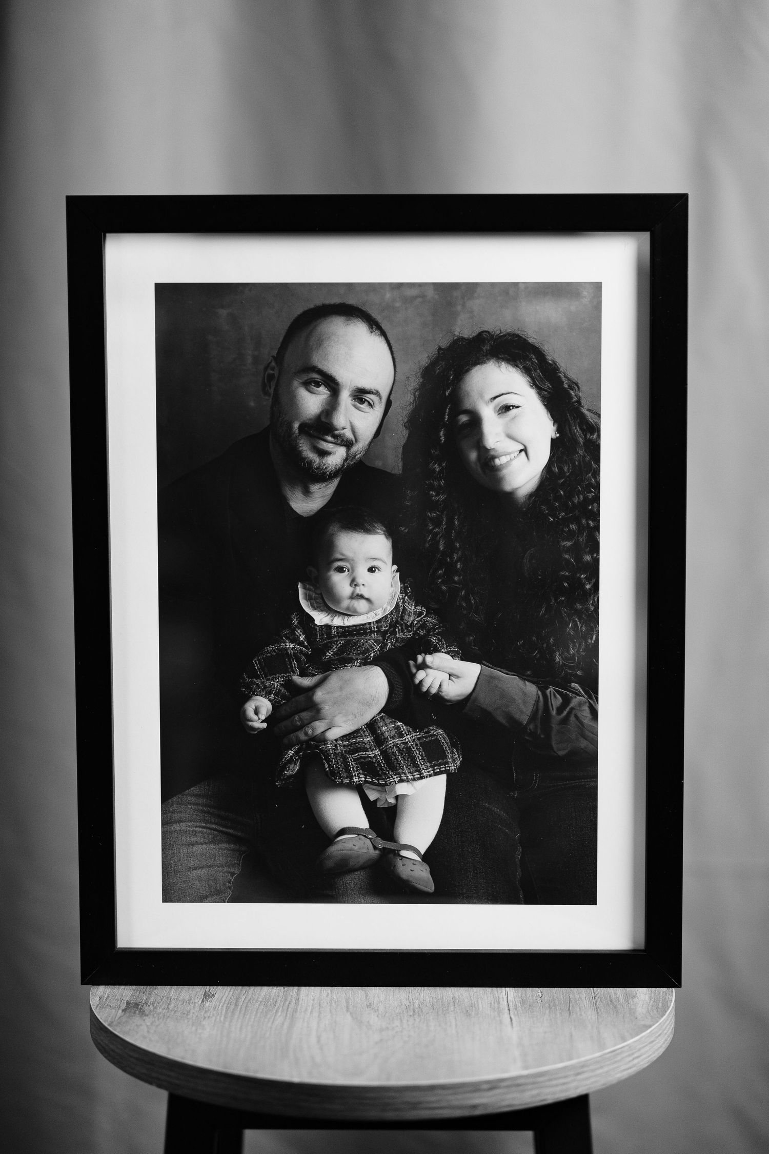 A black and white framed family portrait photograph displayed on a wooden table.