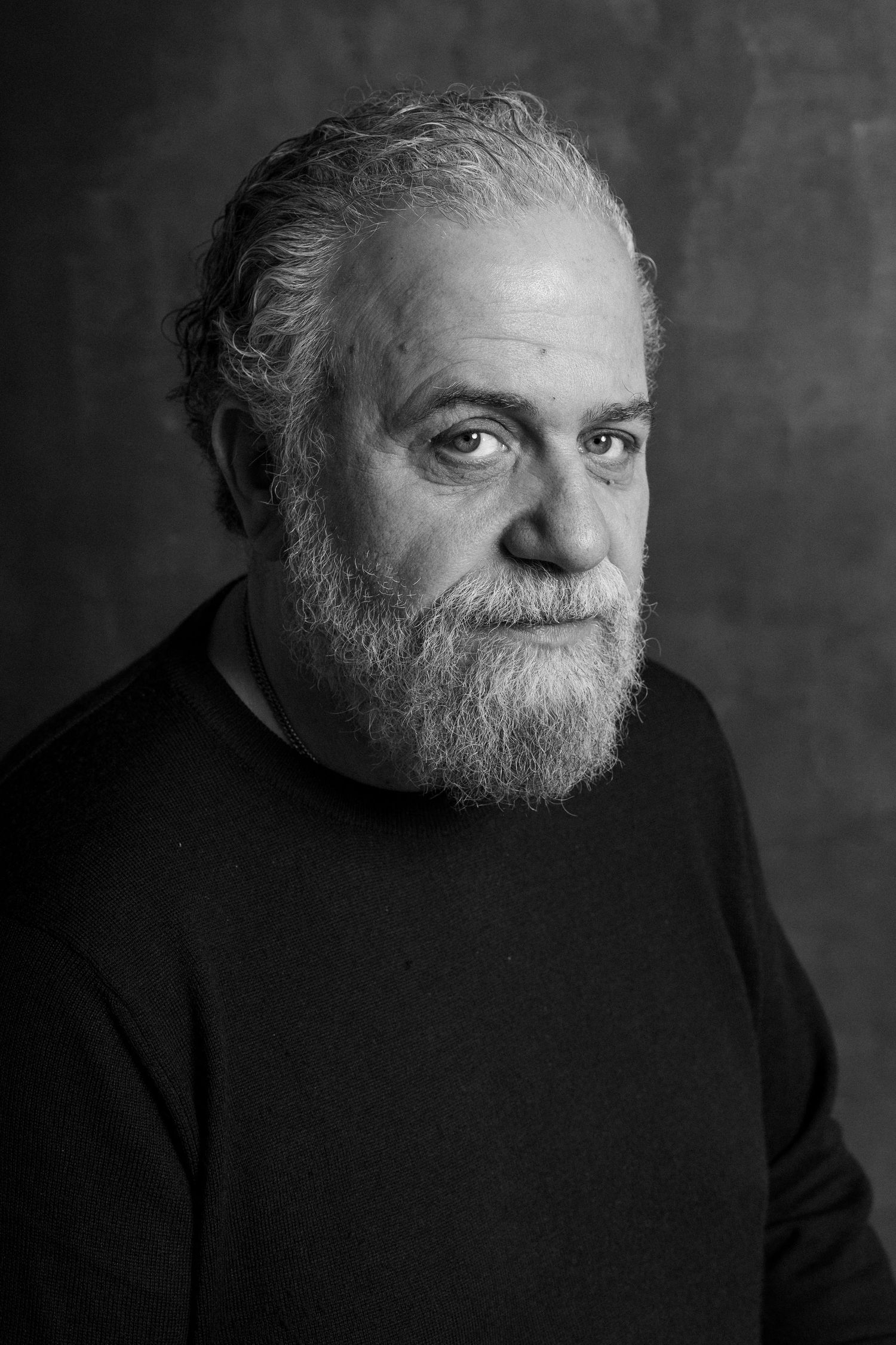 Black and white portrait series showing dramatic lighting on a bearded figure wearing dark clothing against textured background.