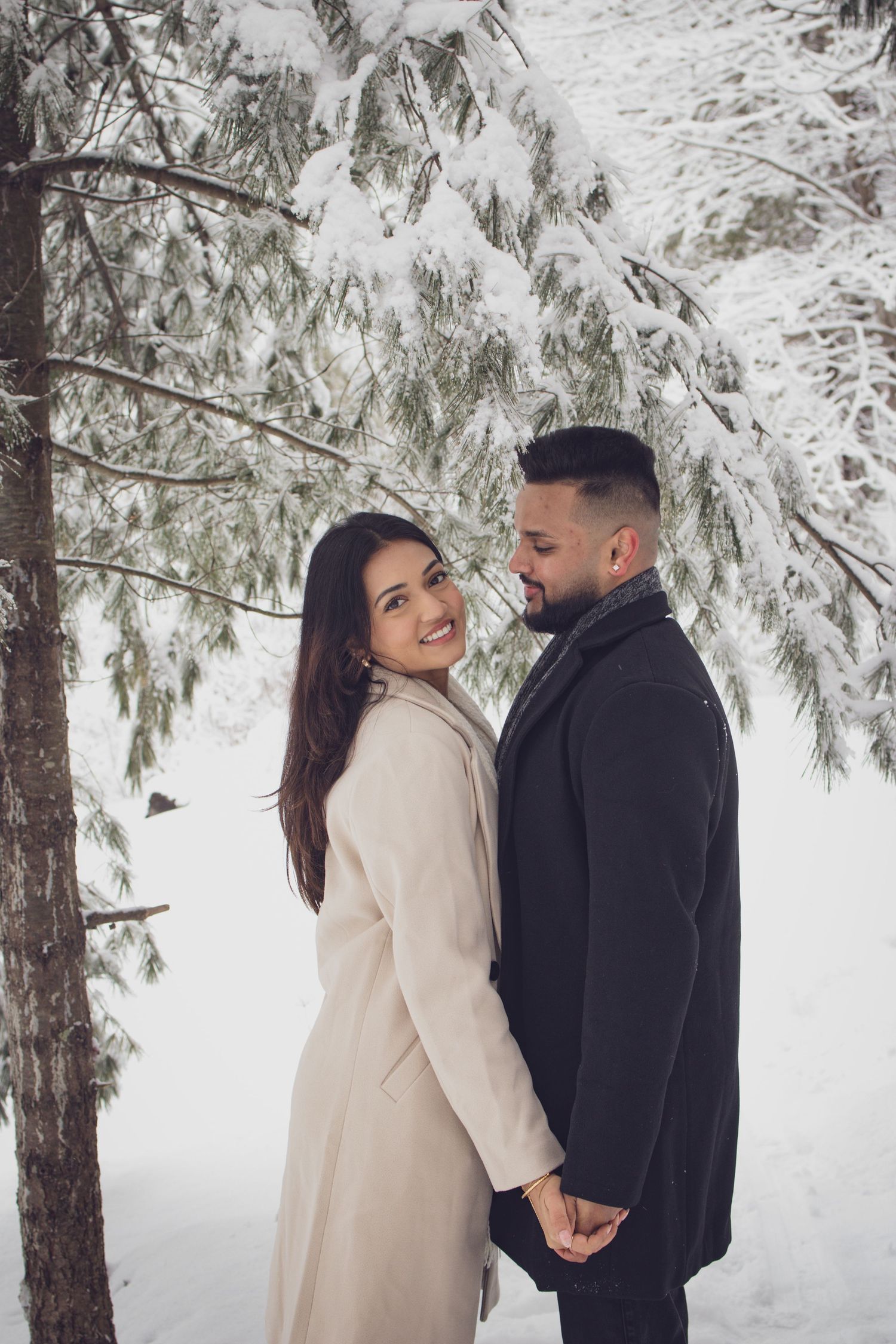 Andover couple photographer capturing a romantic winter session of a couple holding hands and walking through falling snow.