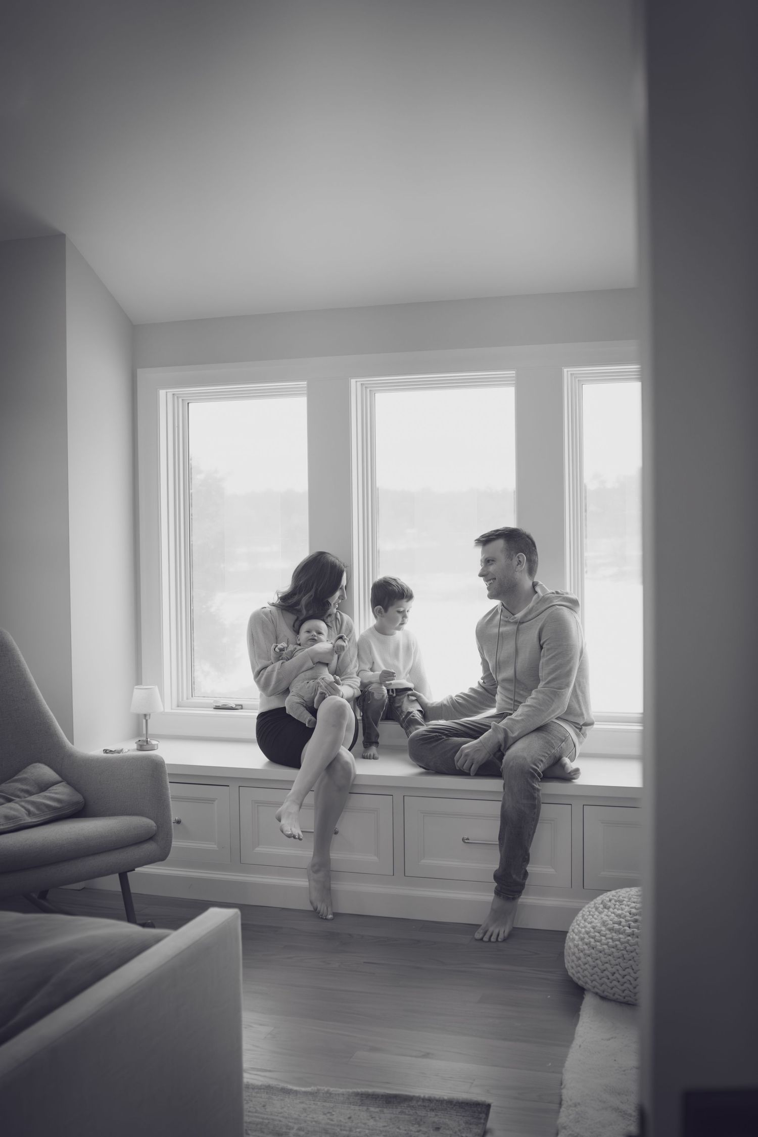 Andover newborn photographer documenting a tender black‑and‑white moment of parents holding their baby during an in‑home lifestyle session.
