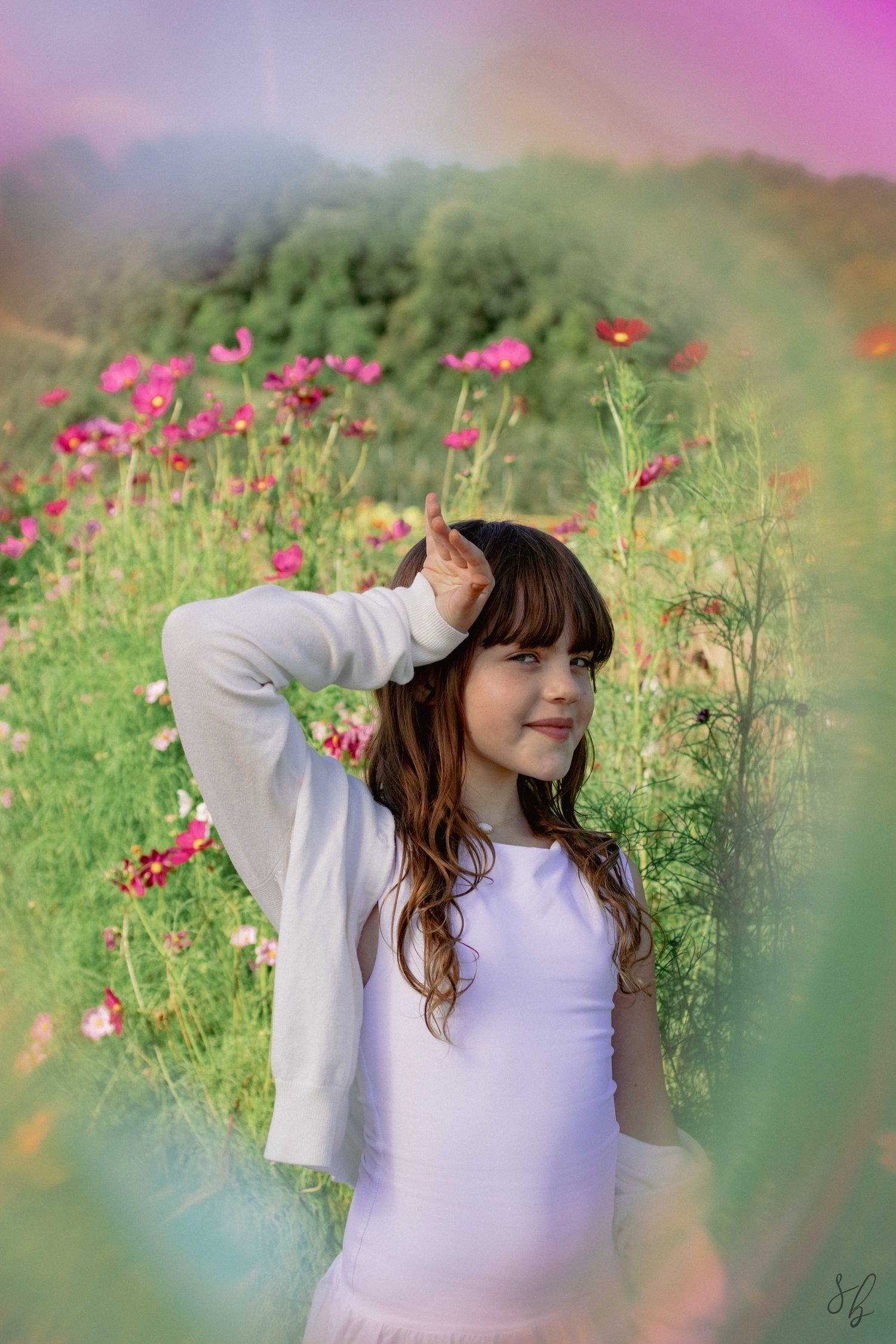 Andover children photographer capturing a natural outdoor portrait of a girl standing in a sunflower field with soft, golden light.