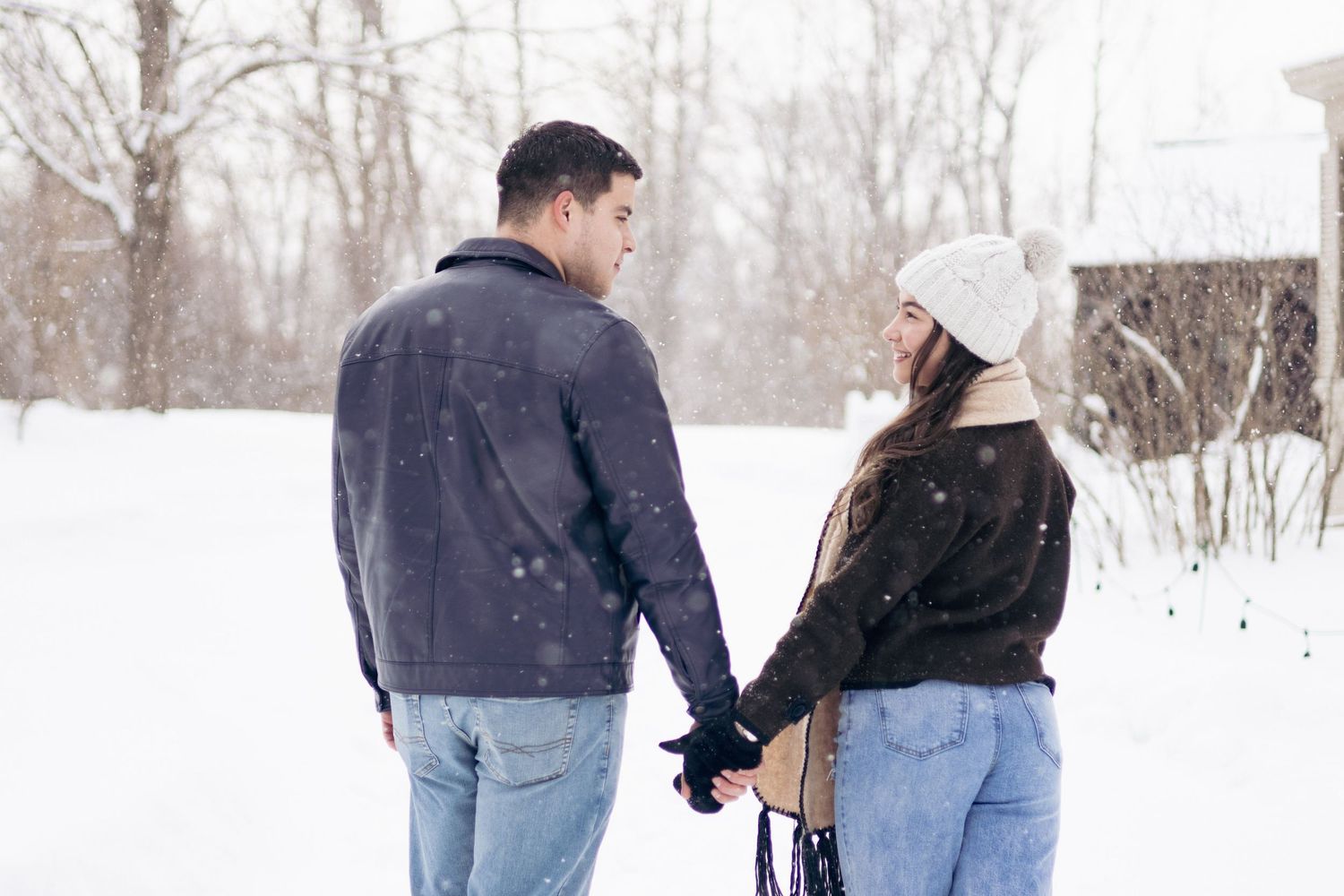 Andover couple photographer capturing a romantic winter session of a couple holding hands and walking through falling snow.