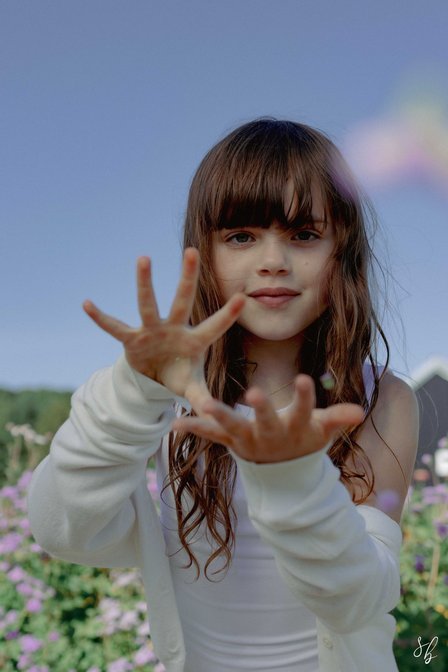 Andover children photographer capturing a natural outdoor portrait of a girl standing in a sunflower field with soft, golden light.