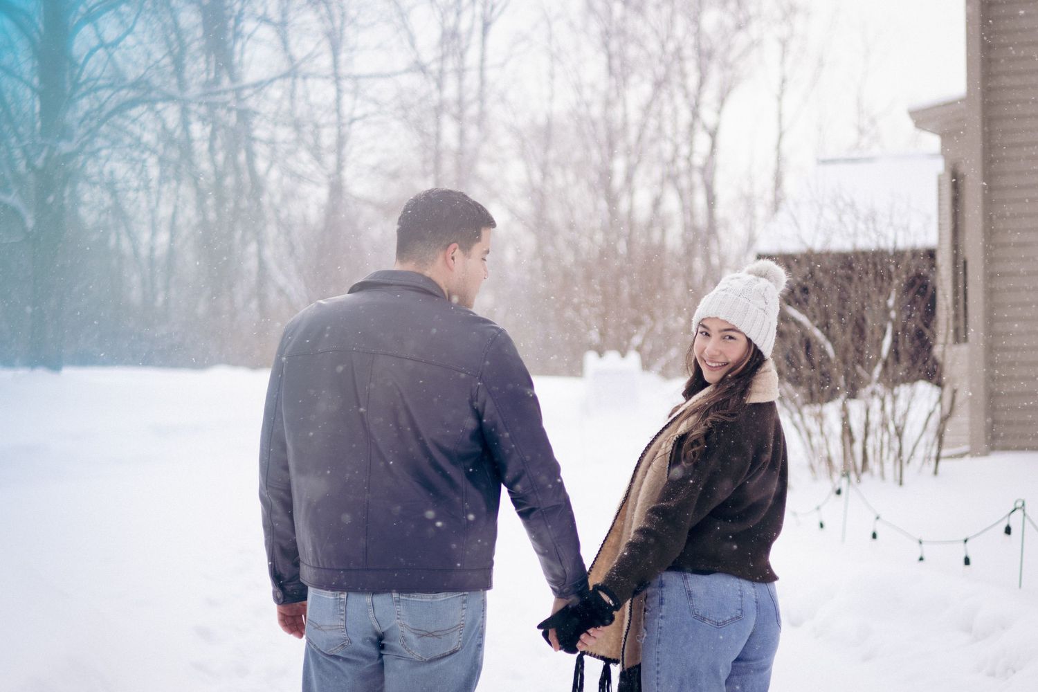 Andover couple photographer capturing a romantic winter session of a couple holding hands and walking through falling snow.
