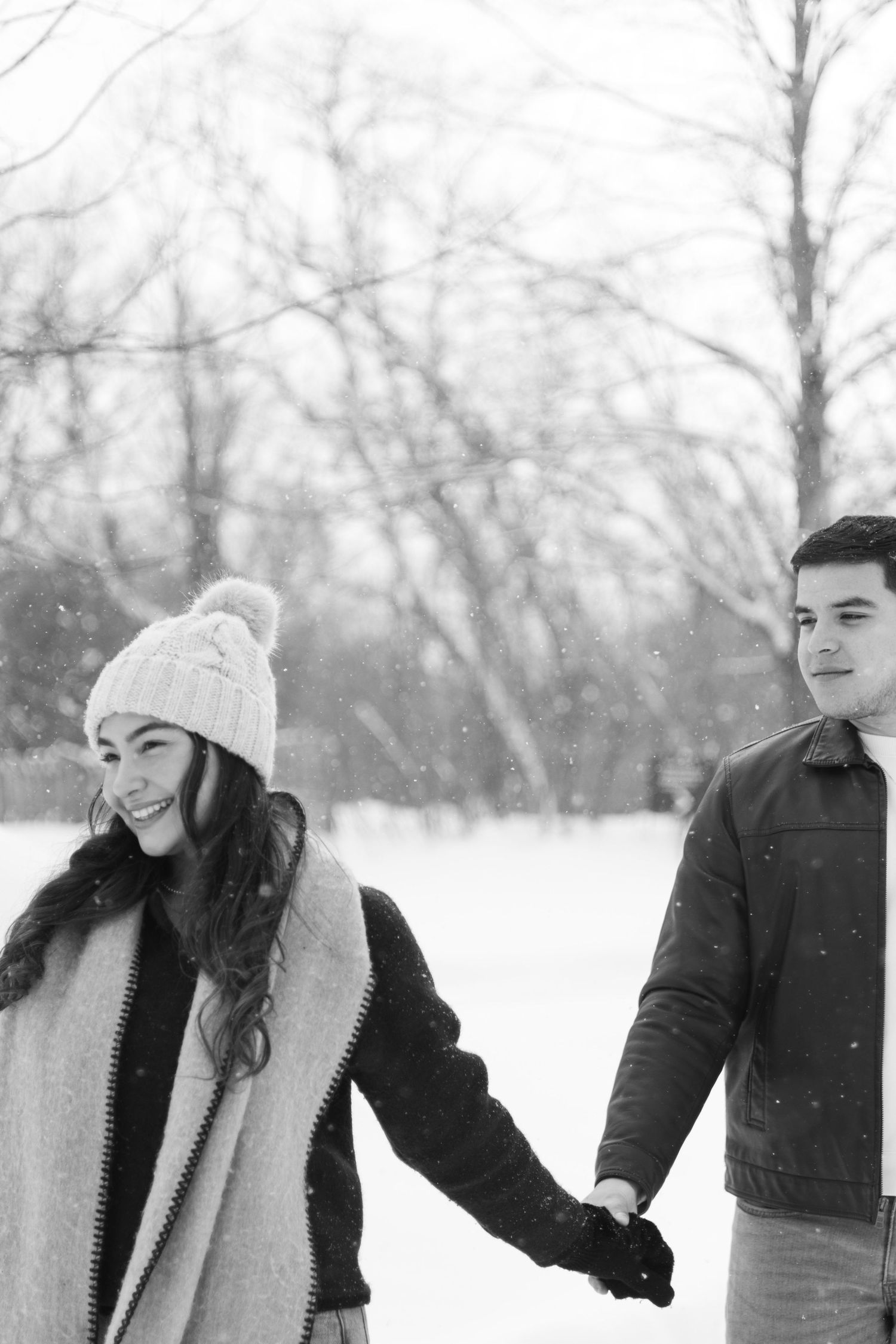 Andover couple photographer capturing a romantic winter session of a couple holding hands and walking through falling snow.