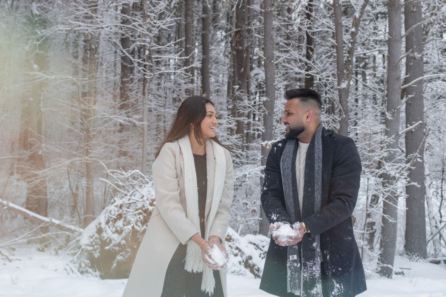 Andover couple photographer capturing a romantic winter session of a couple holding hands and walking through falling snow.