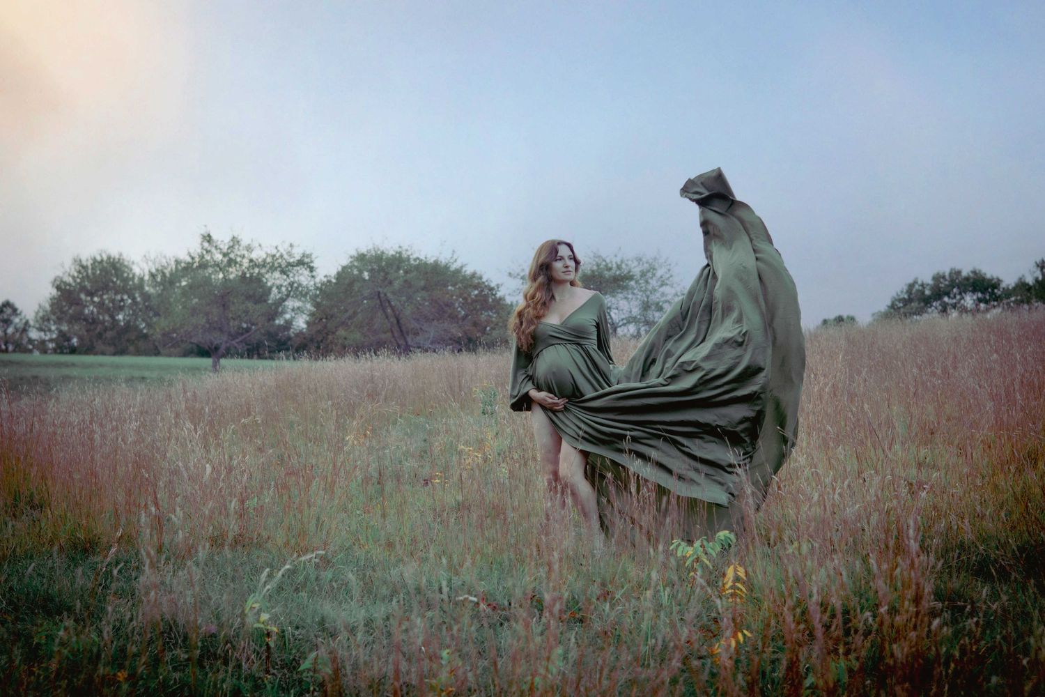Andover portrait photographer capturing an artistic outdoor photo of a woman in a flowing green dress standing in tall grass.