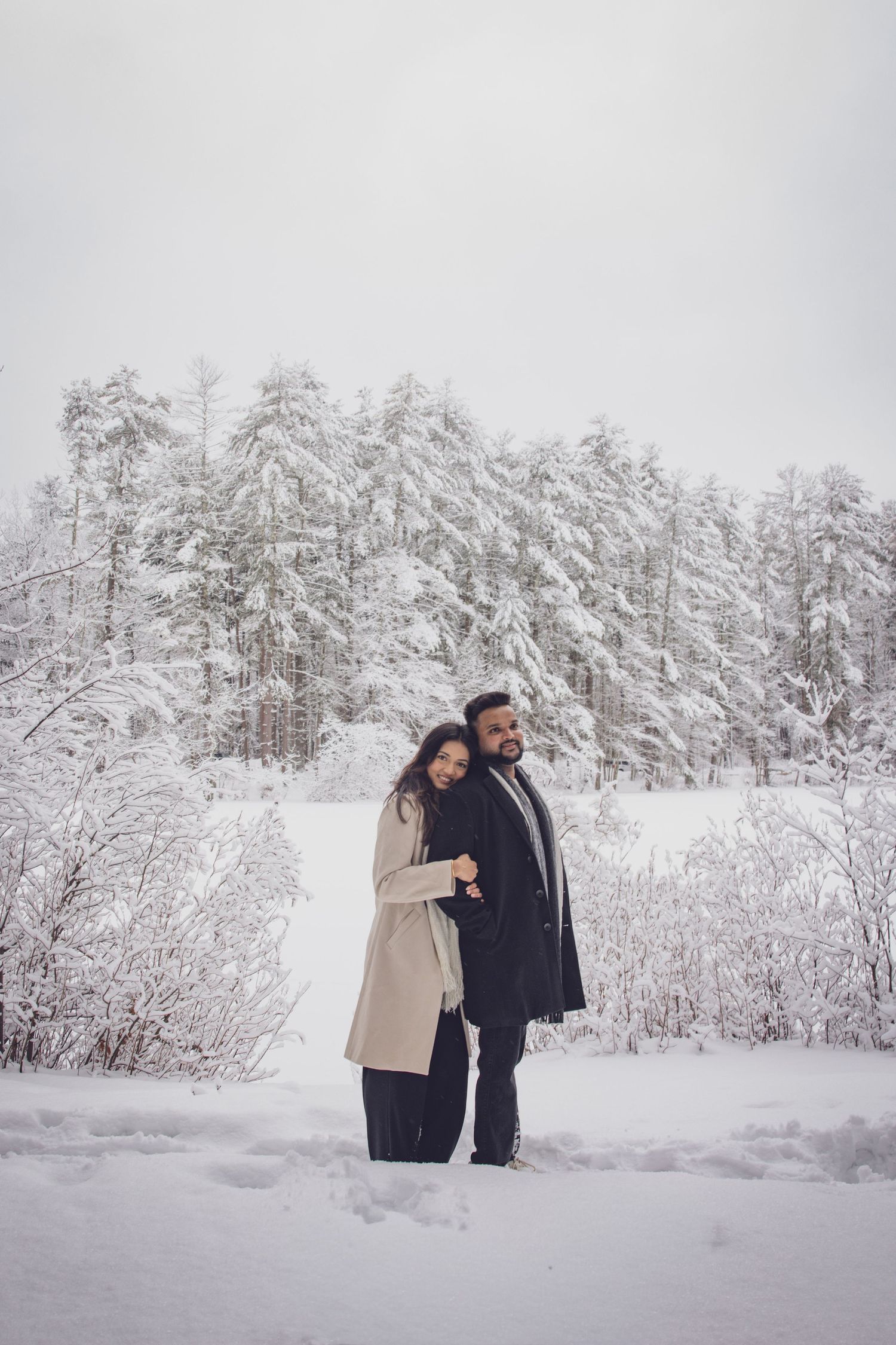 Andover couple photographer capturing a romantic winter session of a couple holding hands and walking through falling snow.