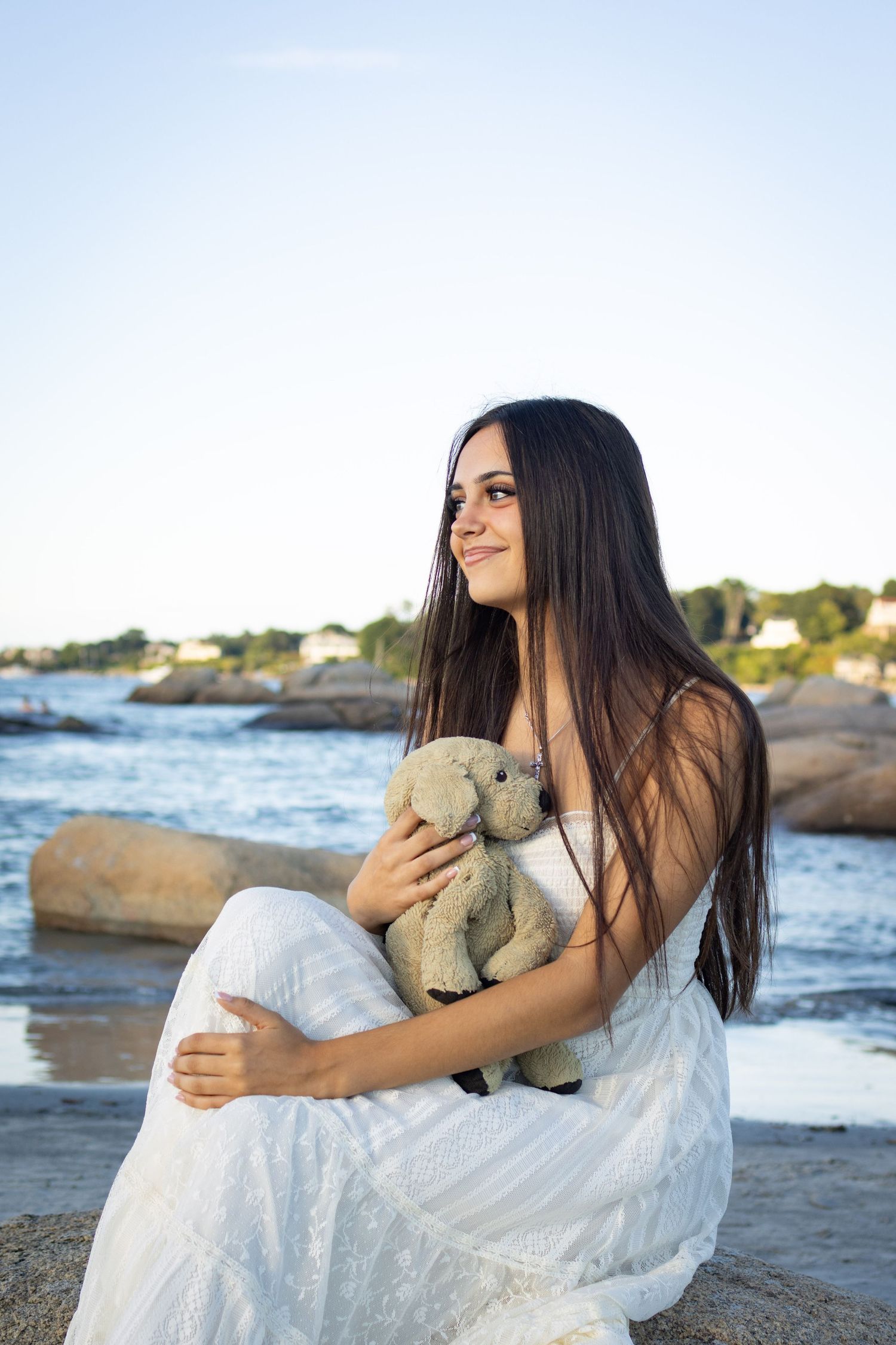 Senior posing at the beach in Gloucester with her childhood teddy bear.