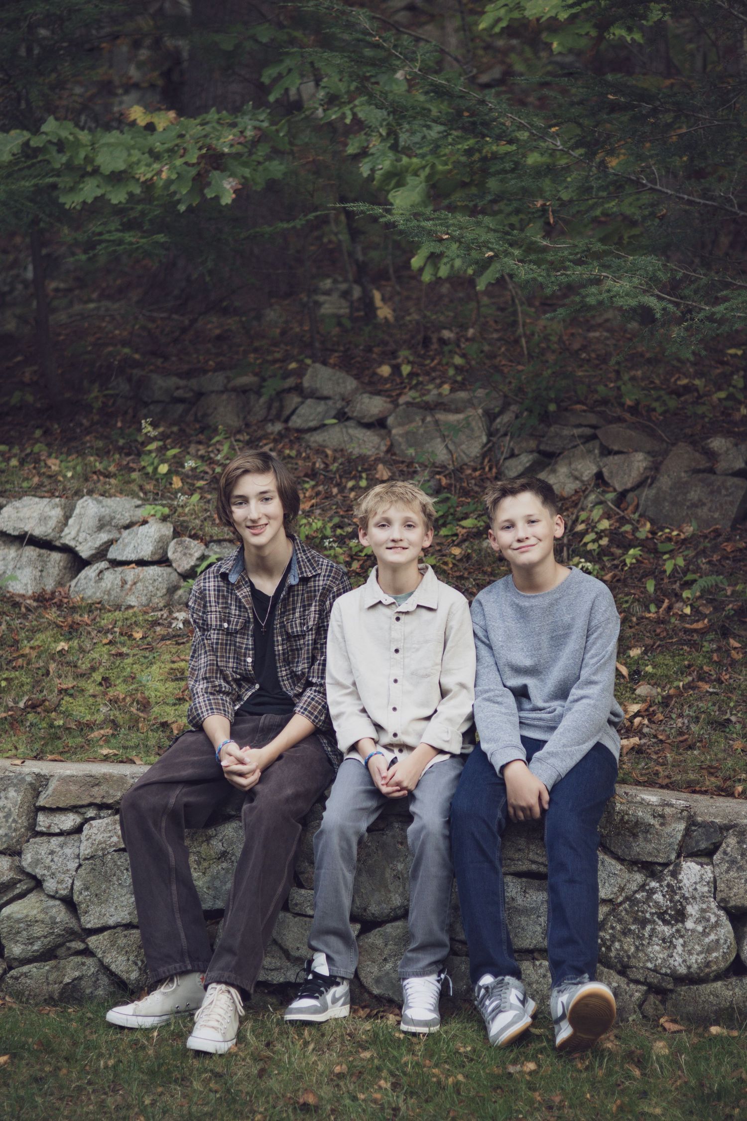 Andover family photographer documenting siblings laughing together during a fall outdoor session in tall grass.