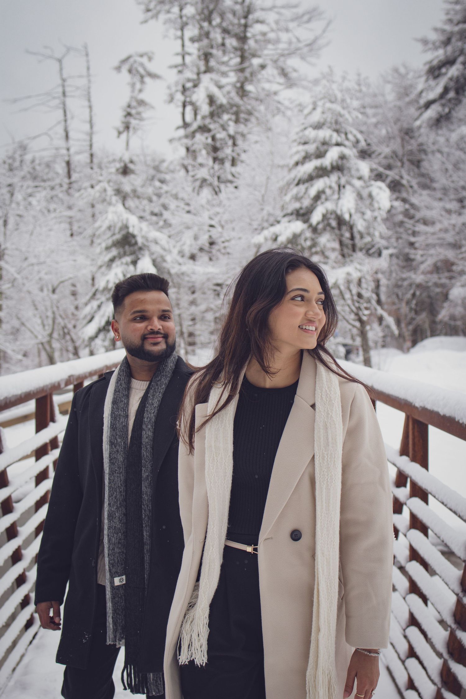 Andover couple photographer capturing a romantic winter session of a couple holding hands and walking through falling snow.