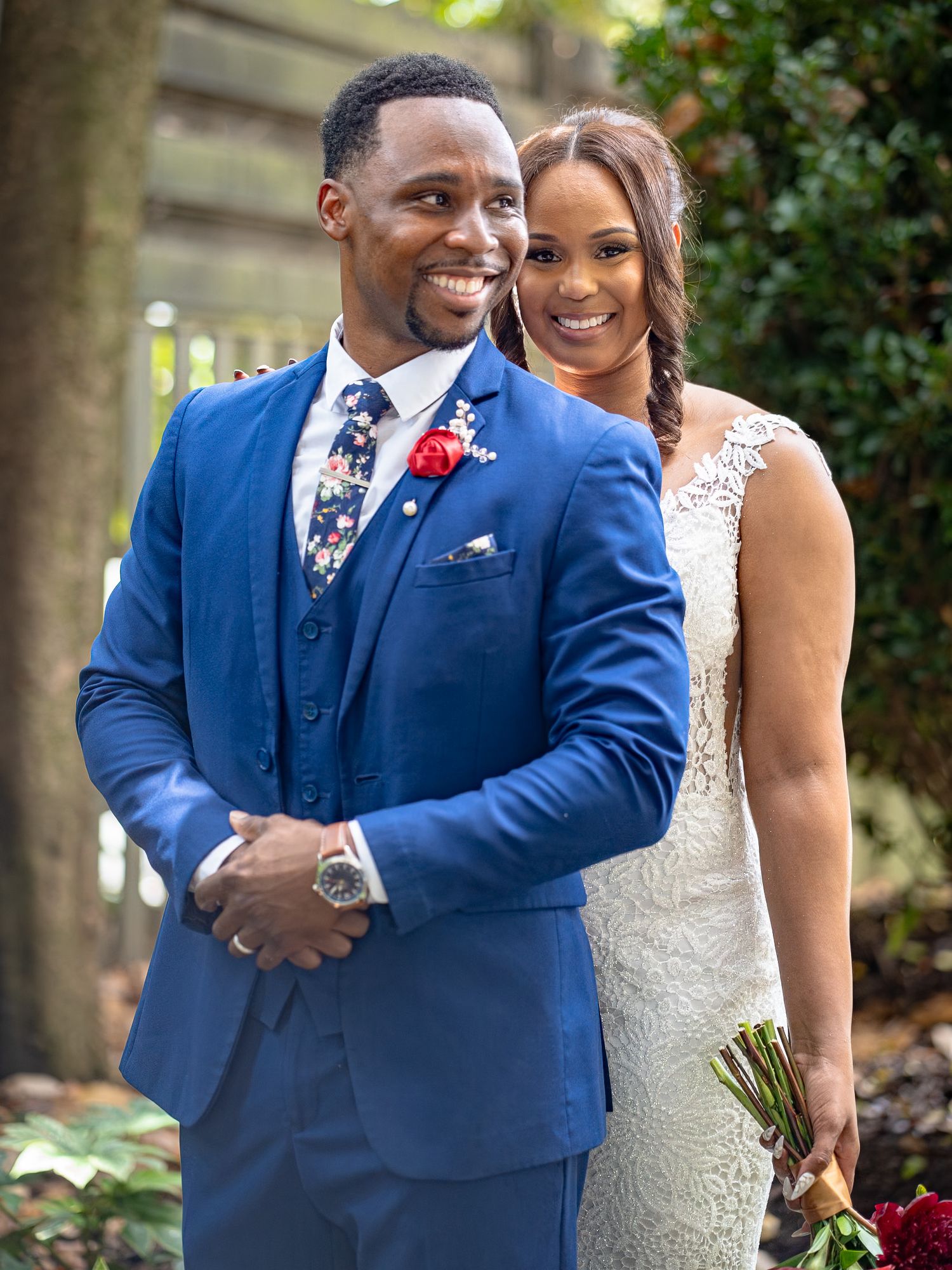 Wedding couple in blue suit and white dress sharing joyful moments in garden setting.