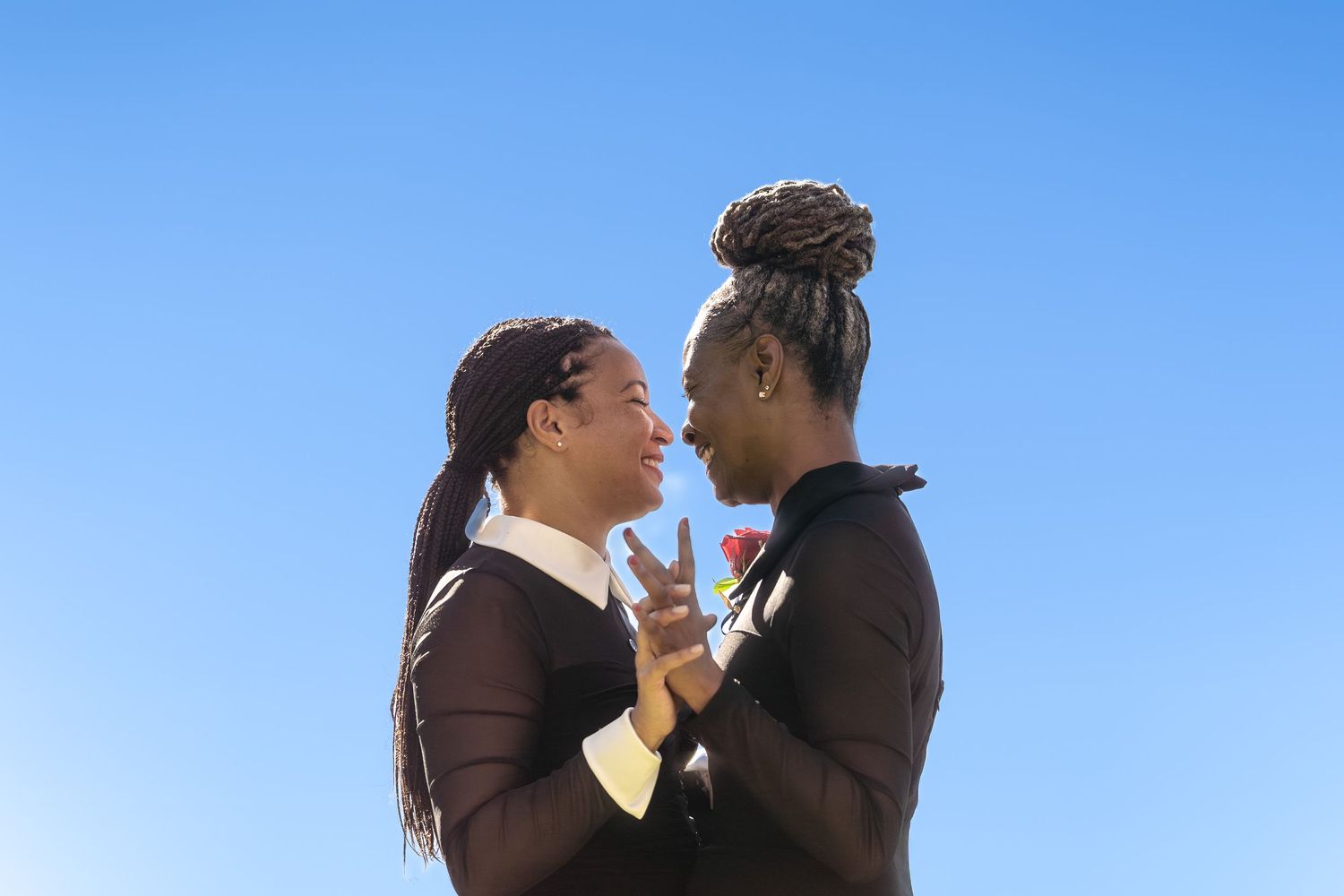 Intimate moment shared against bright blue sky background.
