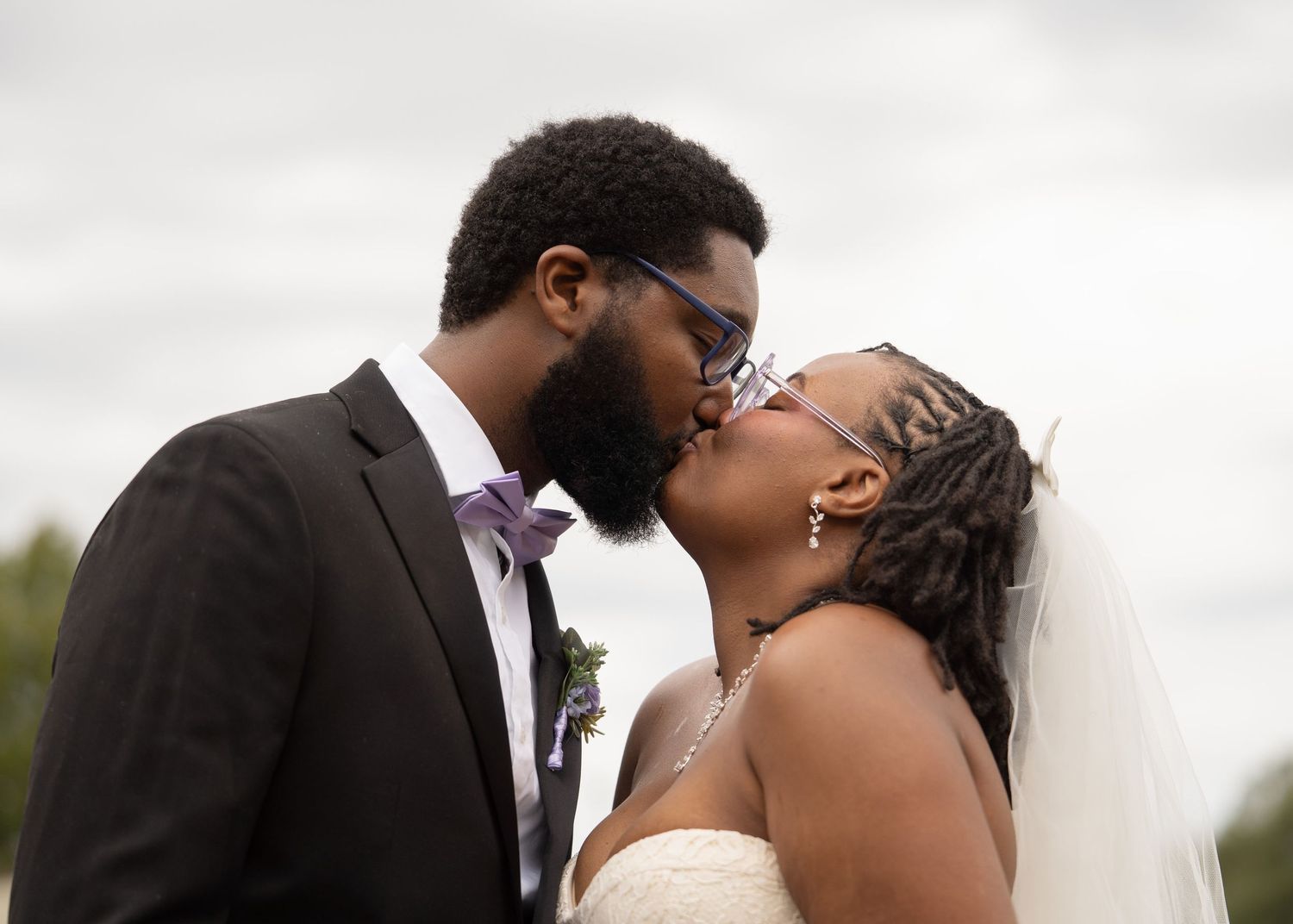 Intimate wedding portrait session against cloudy sky background.