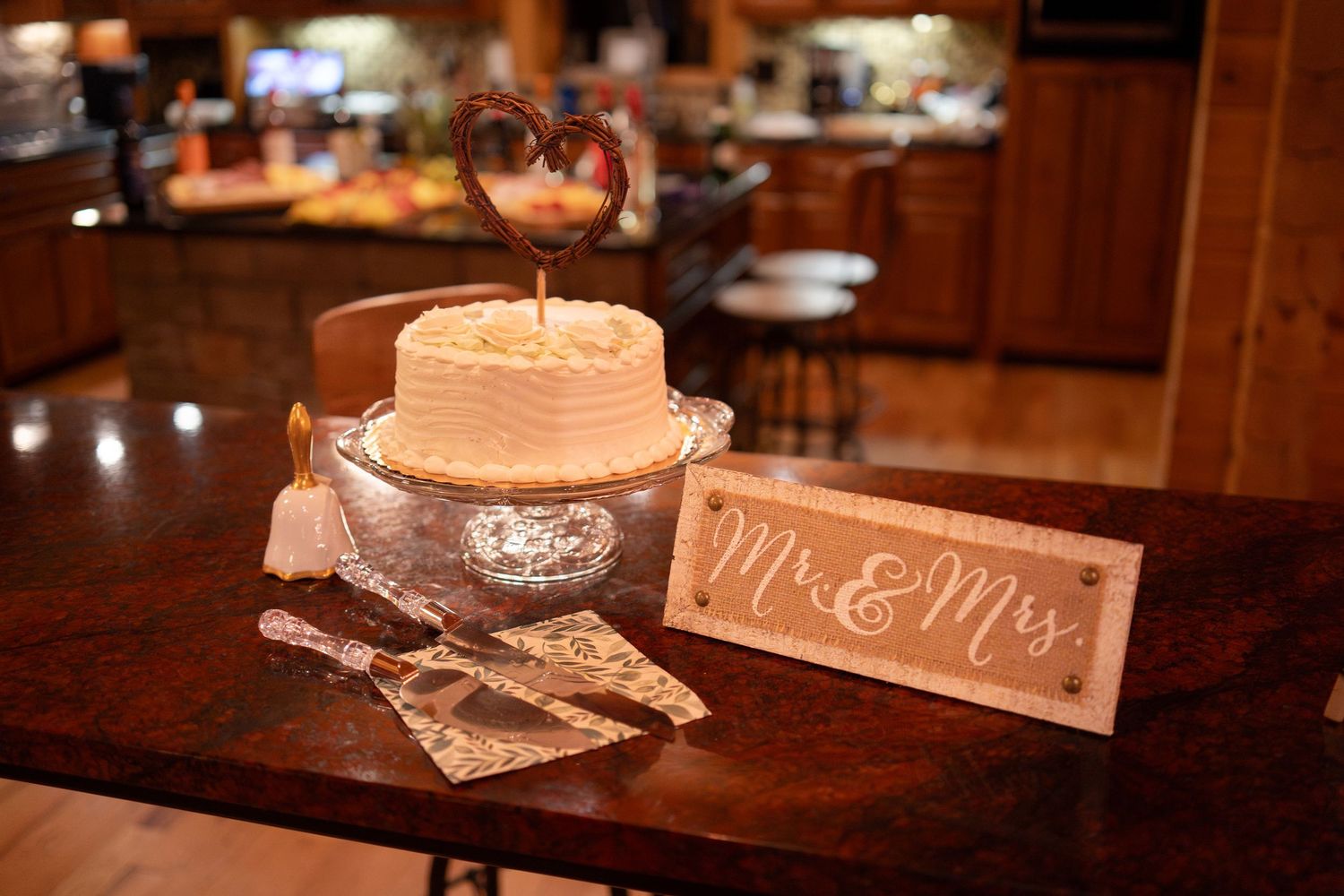 Wedding cake with Mr & Mrs sign on wooden table with cake server.