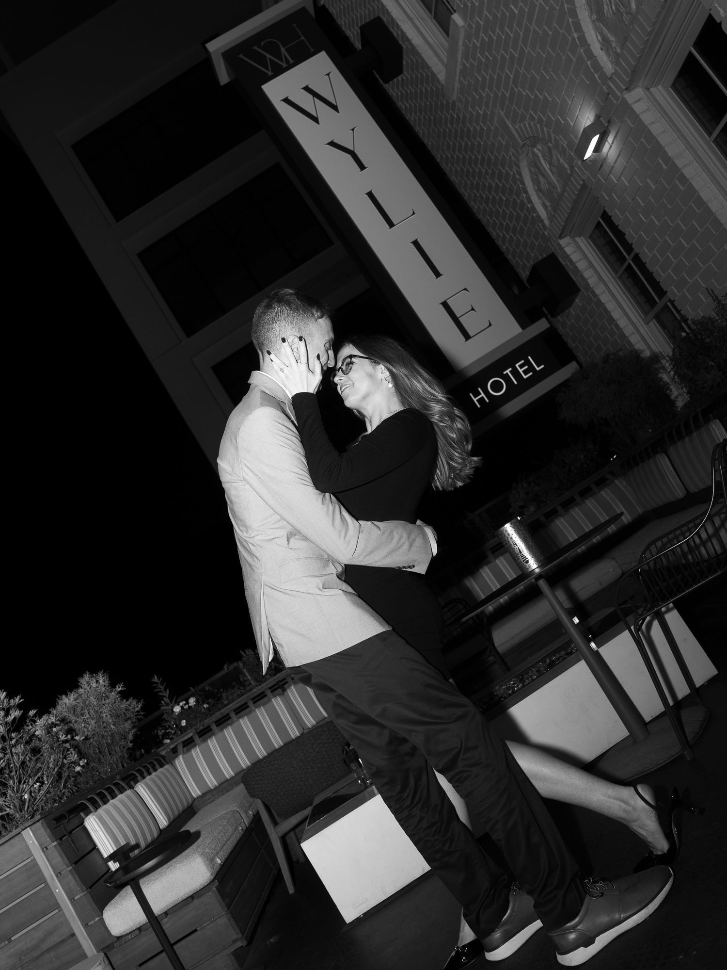 Silhouetted couple dancing together at night outside hotel venue.