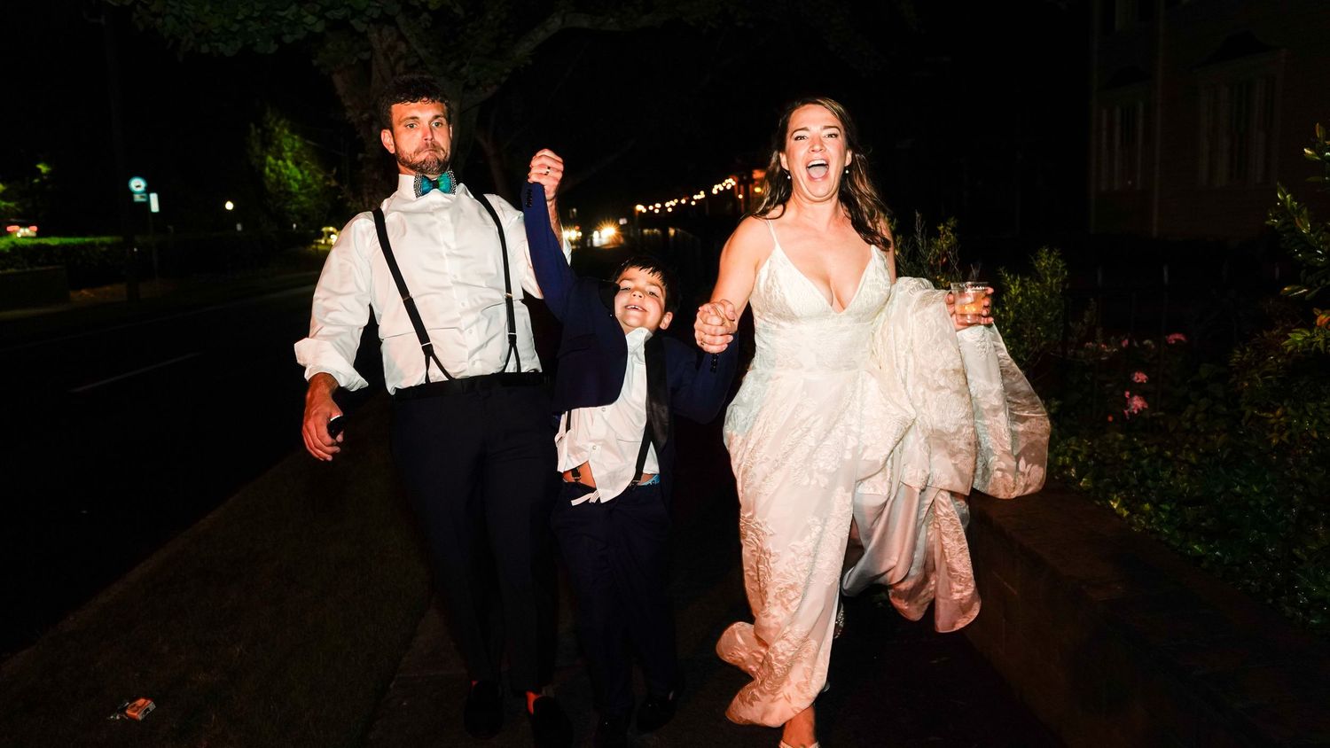 Wedding party dancing at nighttime outdoor reception with string lights.