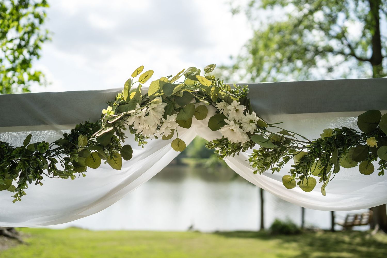 White wedding dresses displayed outdoors with natural lighting and green foliage.