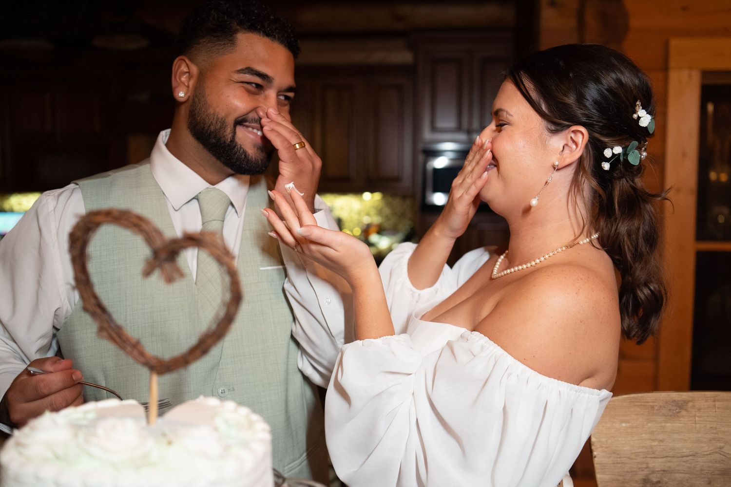 Bride and groom laughing while cutting their wedding cake together.