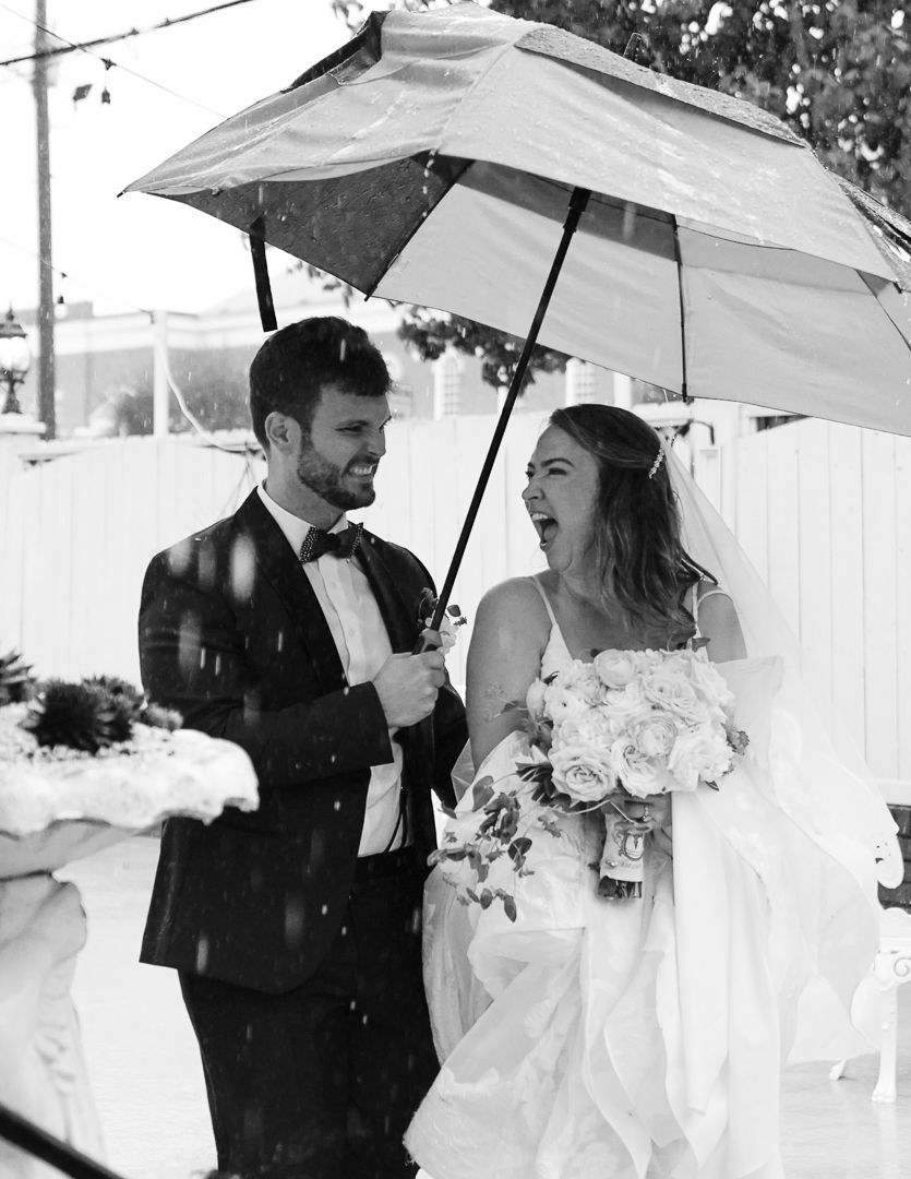 Wedding couple shares intimate moments under umbrellas in the rain.