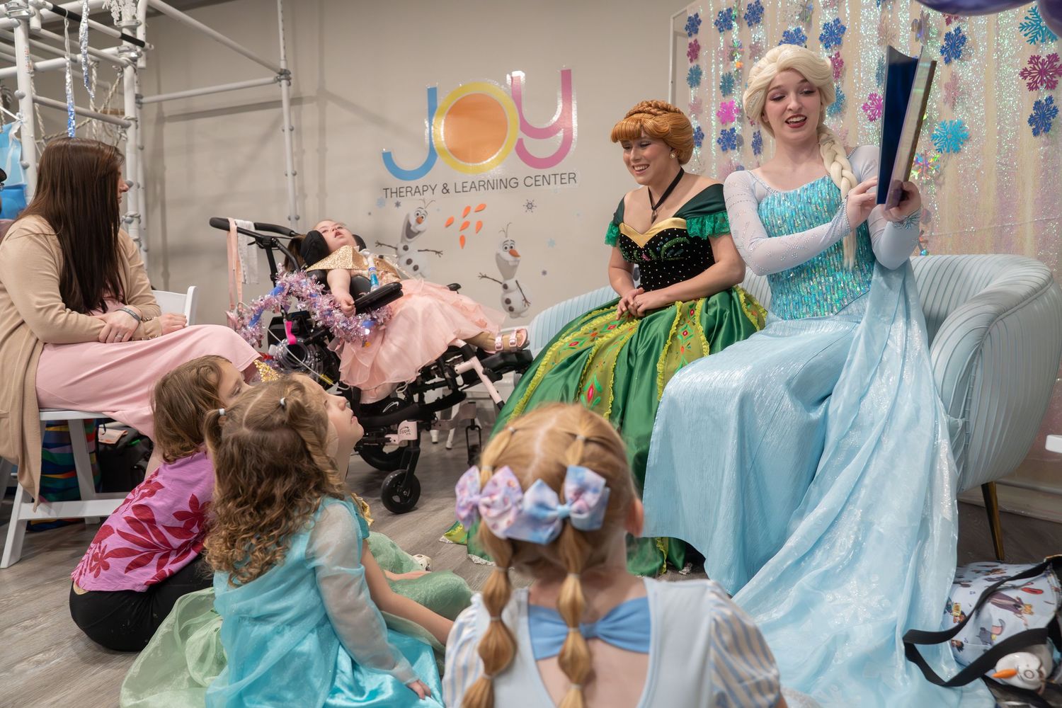 Princess characters Anna and Elsa read to young girls in princess dresses at Joy Learning Center.
