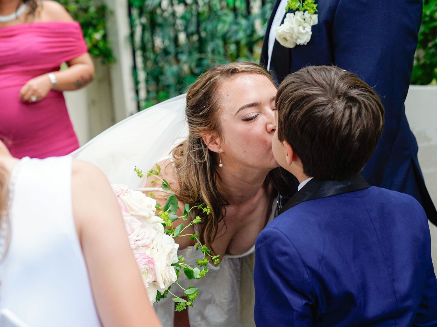 Couple sharing a romantic kiss outdoors surrounded by lush greenery.
